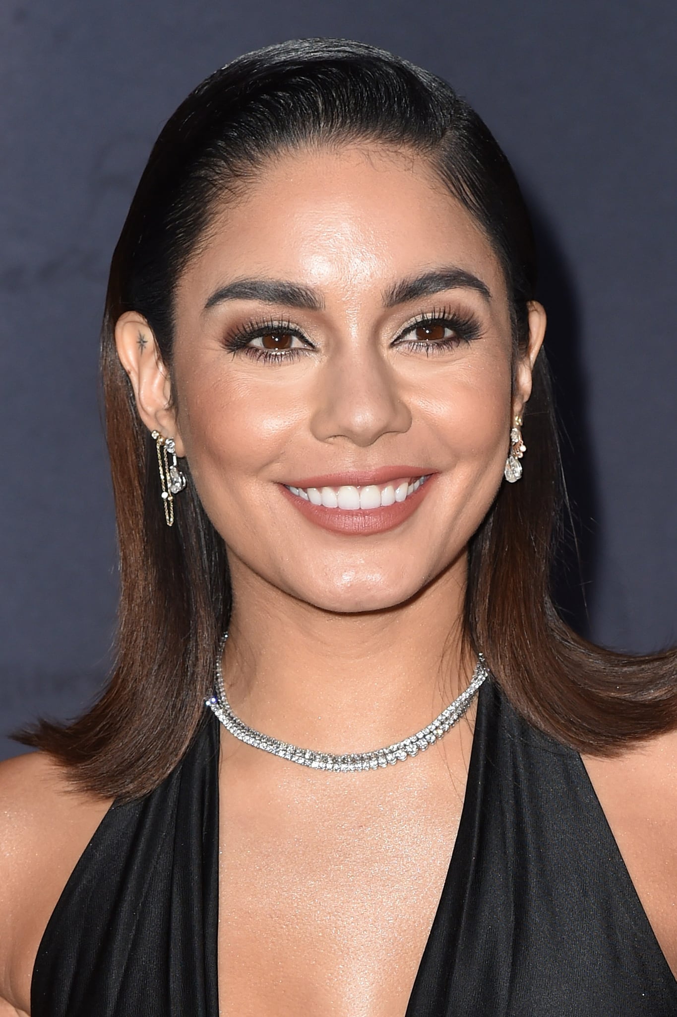 Vanessa Hudgens wears smokey eye-makeup with mascara and a slick side-parted 'do with flared-out ends