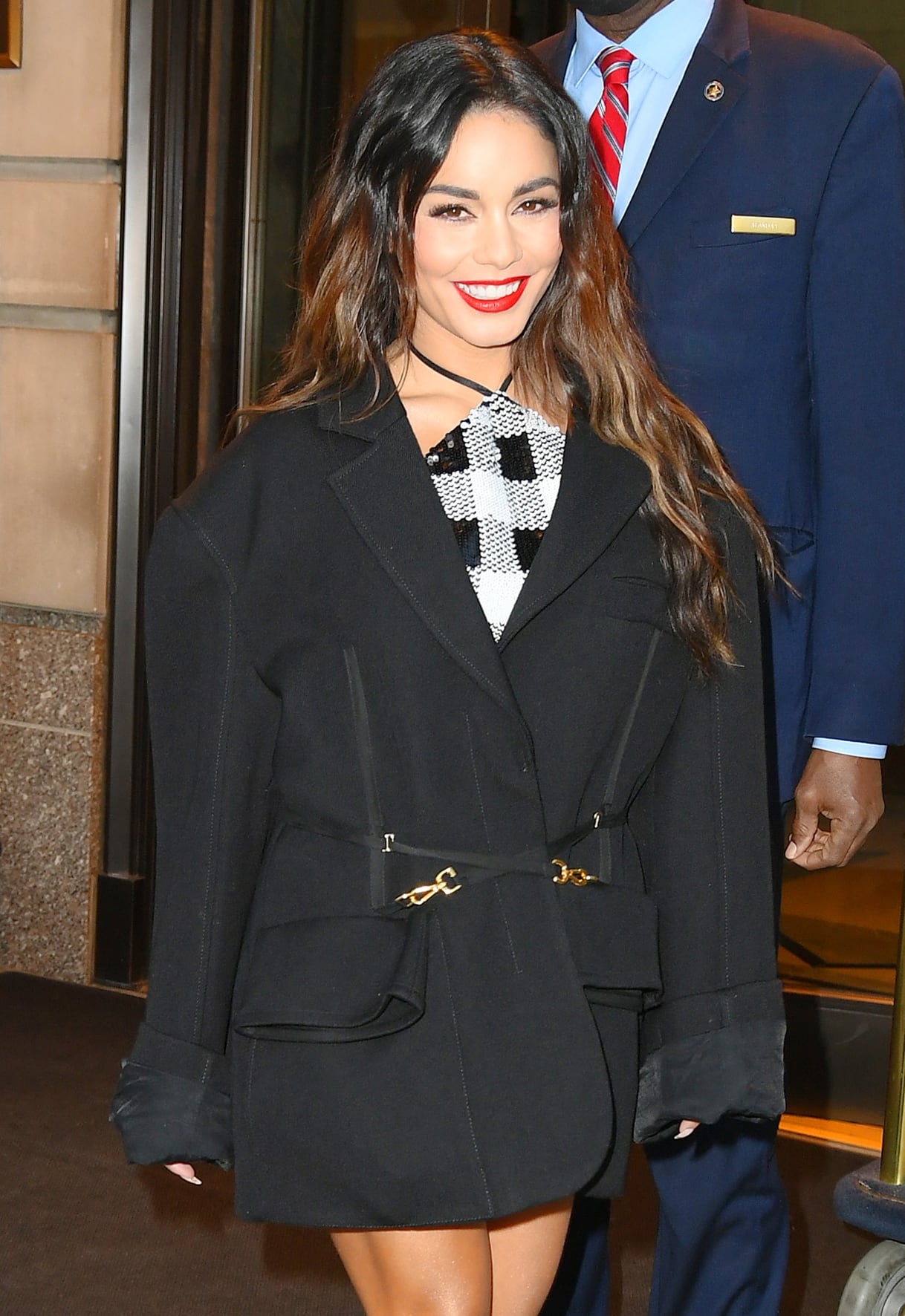 Vanessa Hudgens adds a pop of bold red lip color to the look and styles her long tresses in tousled waves