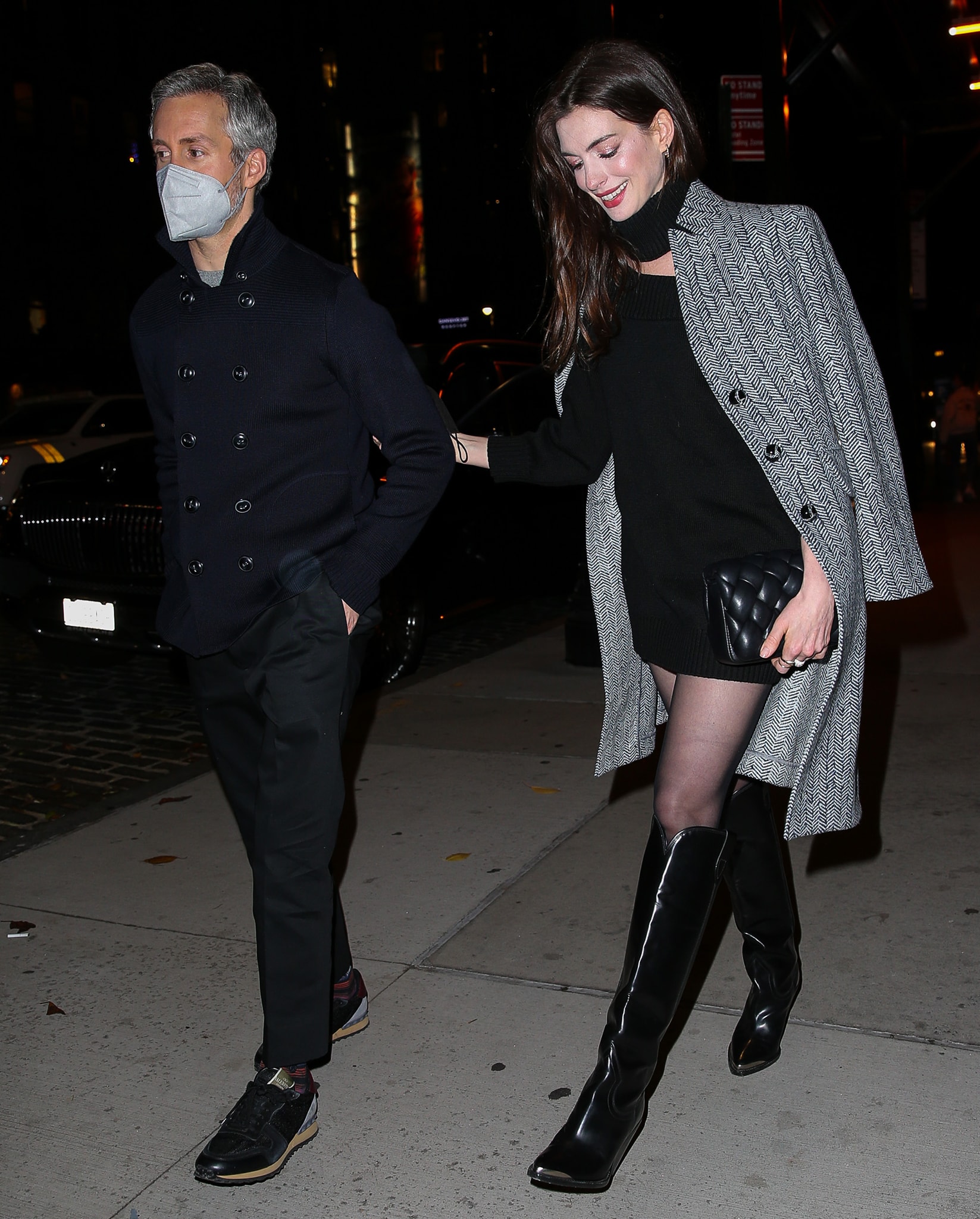 Adam Shulman wears a navy peacoat while Anne Hathaway bundles up in a herringbone coat and a black Monse sweater dress