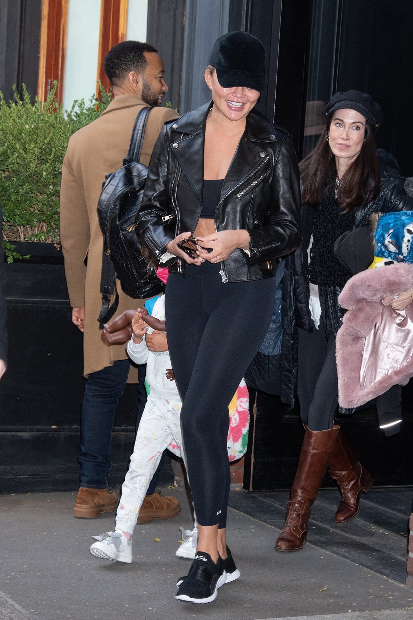 Chrissy Teigen opts for a sleek athleisure in a black bandeau top, Splits59 leggings, and Gucci black leather motorcycle jacket