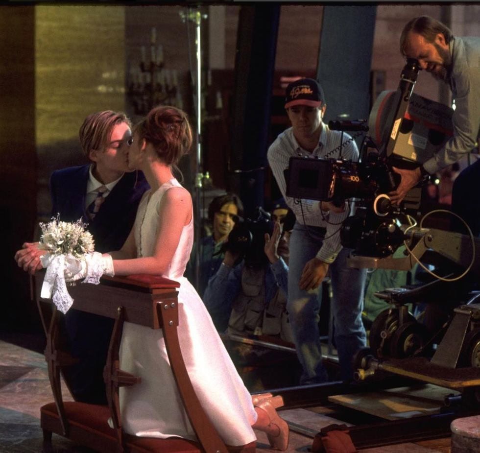 Claire Danes kneels in a simple white dress and blush Mary Jane block-heel pumps as Leonardo DiCaprio, in a slim navy suit, kisses her during the secret chapel wedding in Romeo + Juliet