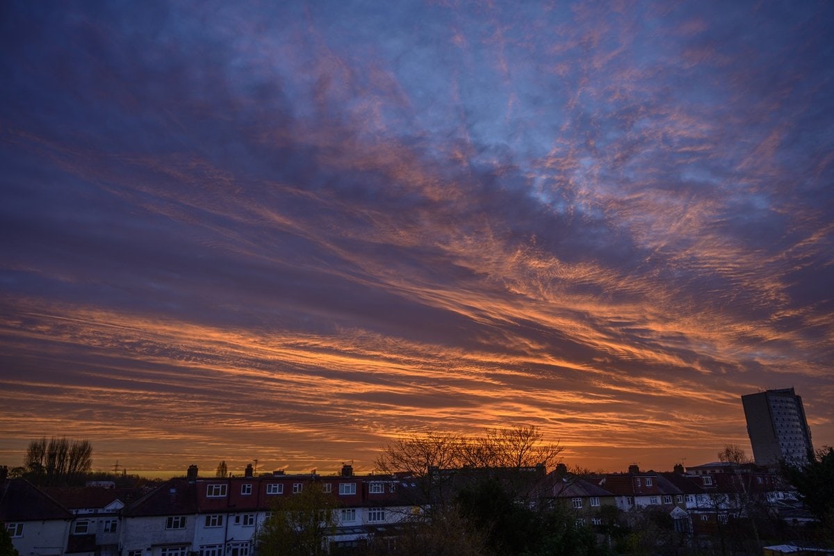 Dawn over southwest London with dramatic colorful clouds lit by the rising sun and suburban houses in the foreground