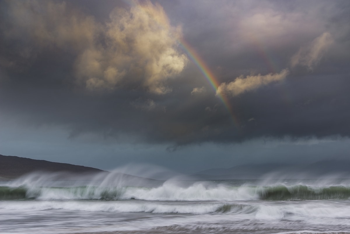 Dramatic light and stormy weather on Luskentyre beach at sunrise with incoming rain and big crashing waves