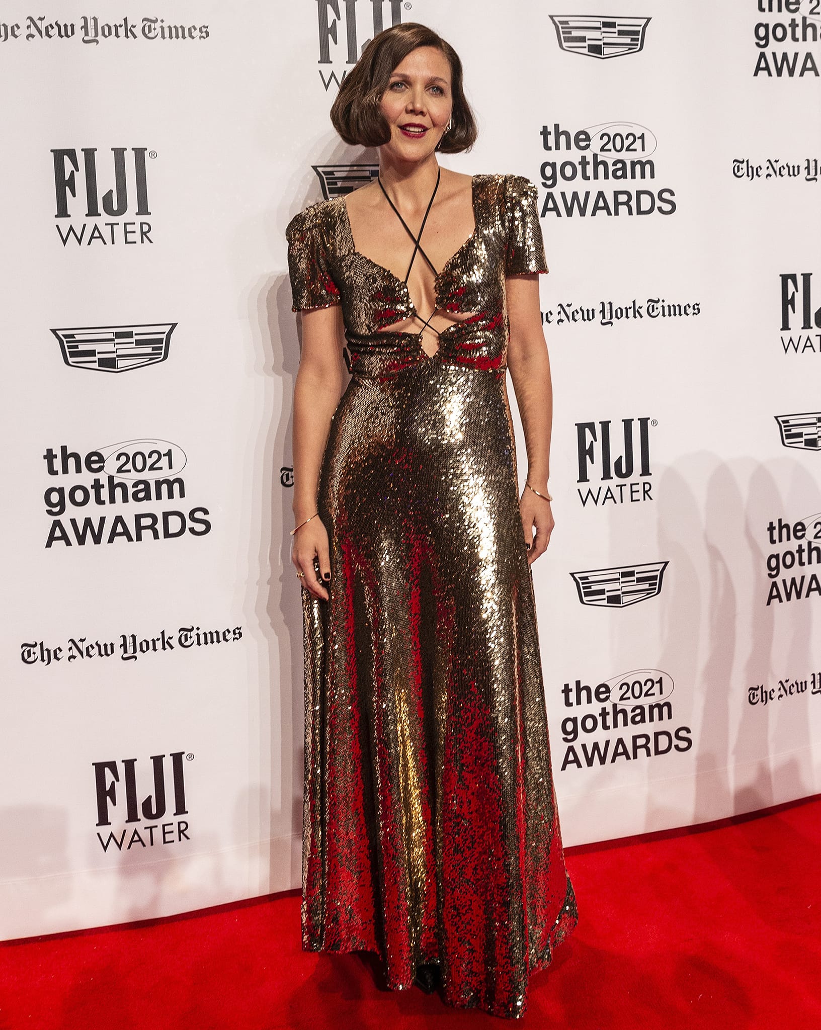 Maggie Gyllenhaal showcases cleavage and underboob in a gold sequin Rodarte Fall 2021 gown