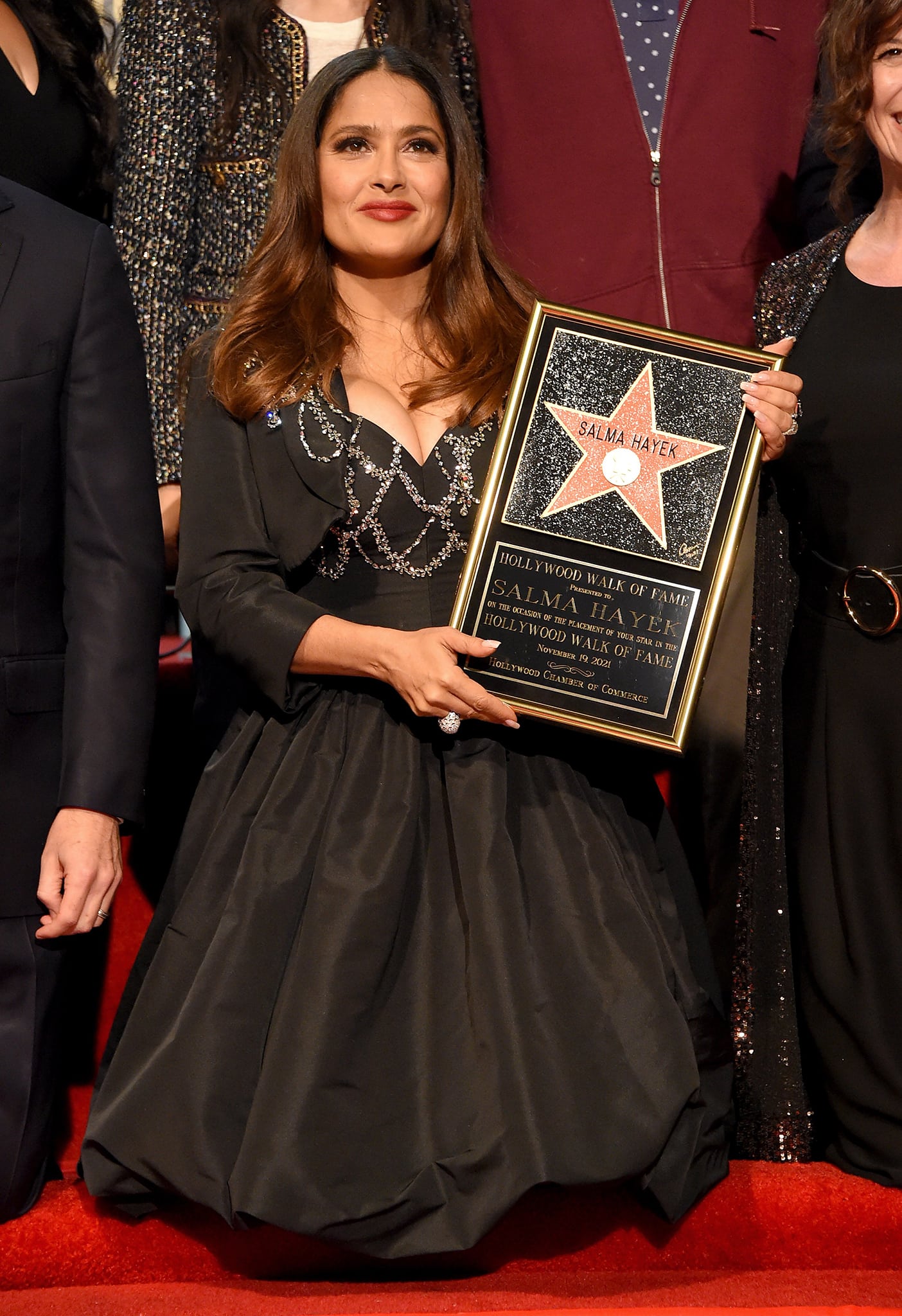 Salma Hayek styles her tresses in bouncy waves and wears cherry red lip color and smokey eyeshadow