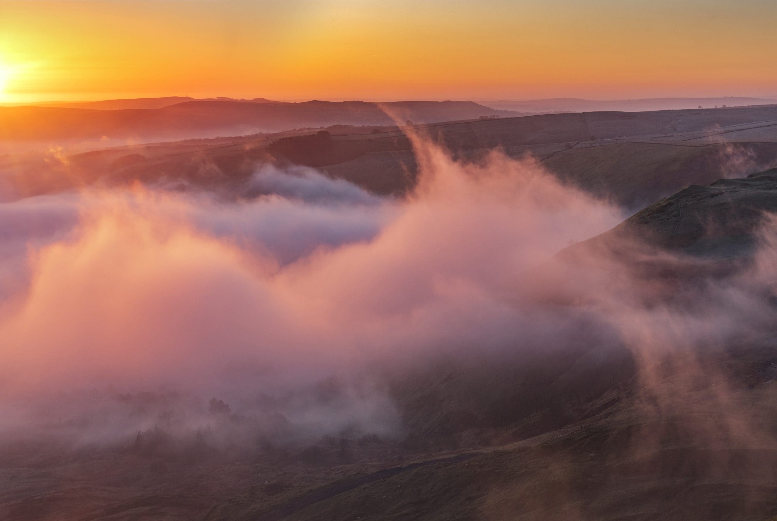 The winter sun rises with intense fog over Hope Valley in Derbyshire