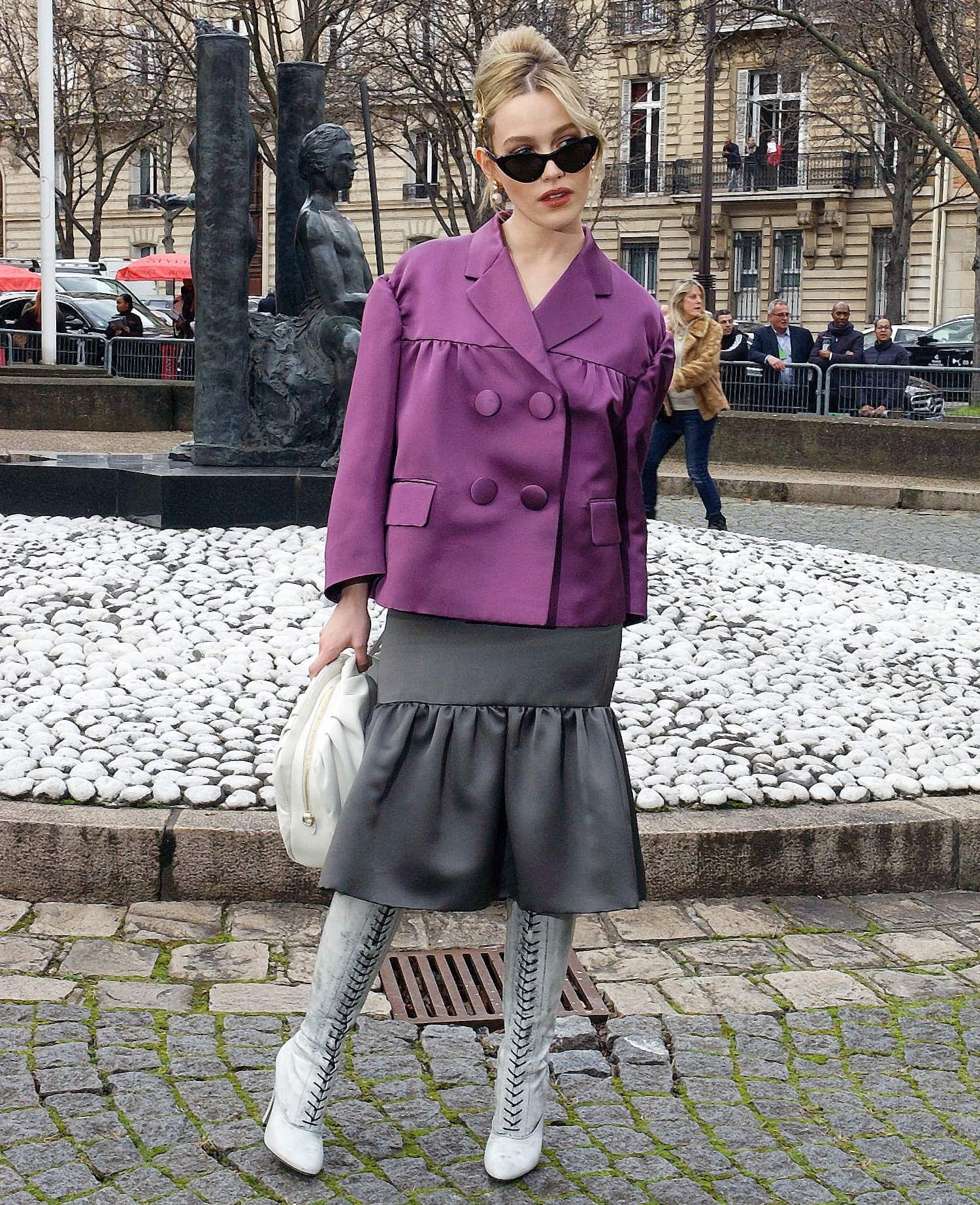 Sydney Sweeney stuns in a bold purple jacket paired with a statement ruffled skirt and lace-up knee-high boots during Paris Fashion Week