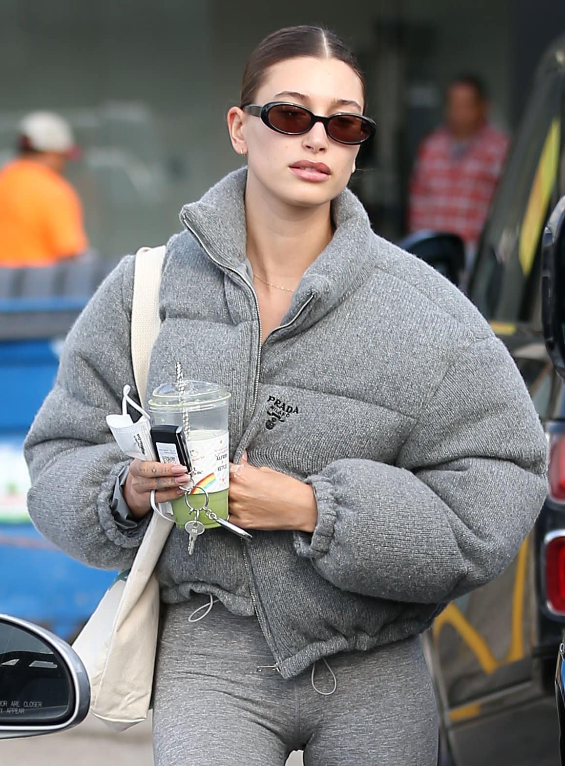 Hailey Bieber pulls her tresses into her signature center-parted bun and wears minimal makeup with DMY by DMY sunglasses