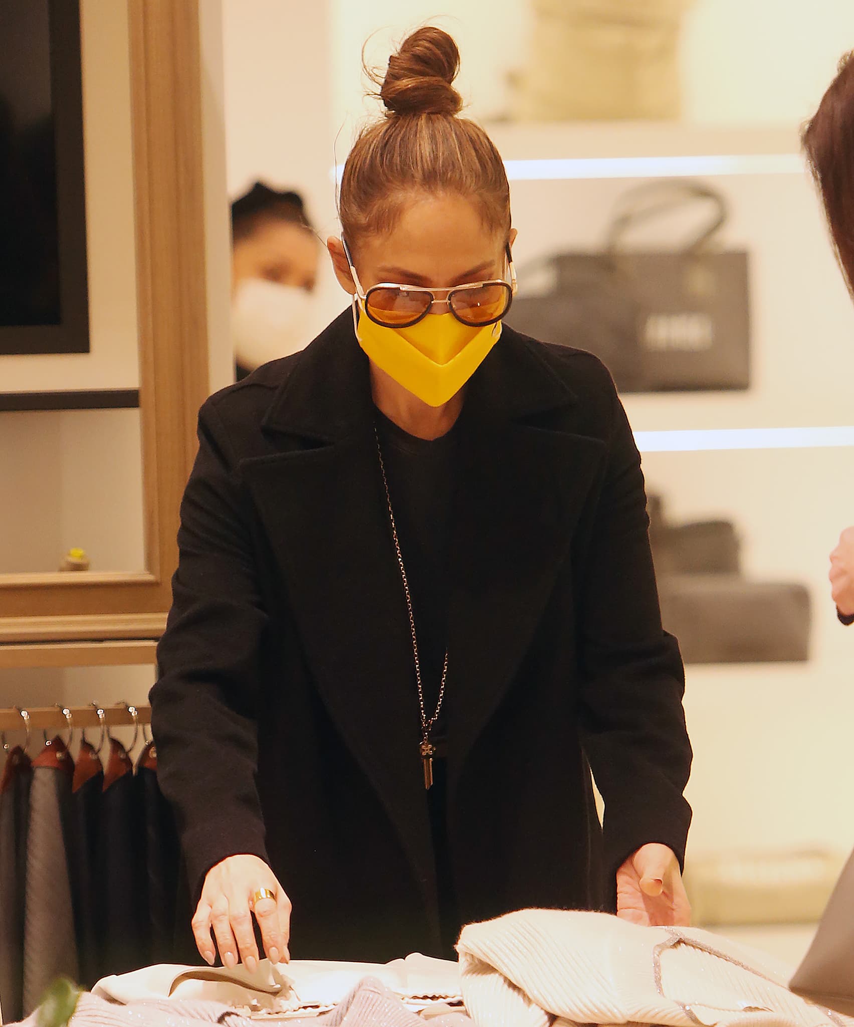Jennifer Lopez wears her tresses in a high bun and adds a pop of color to her monochromatic black look with Henry yellow face mask and Isabel Marant sunnies
