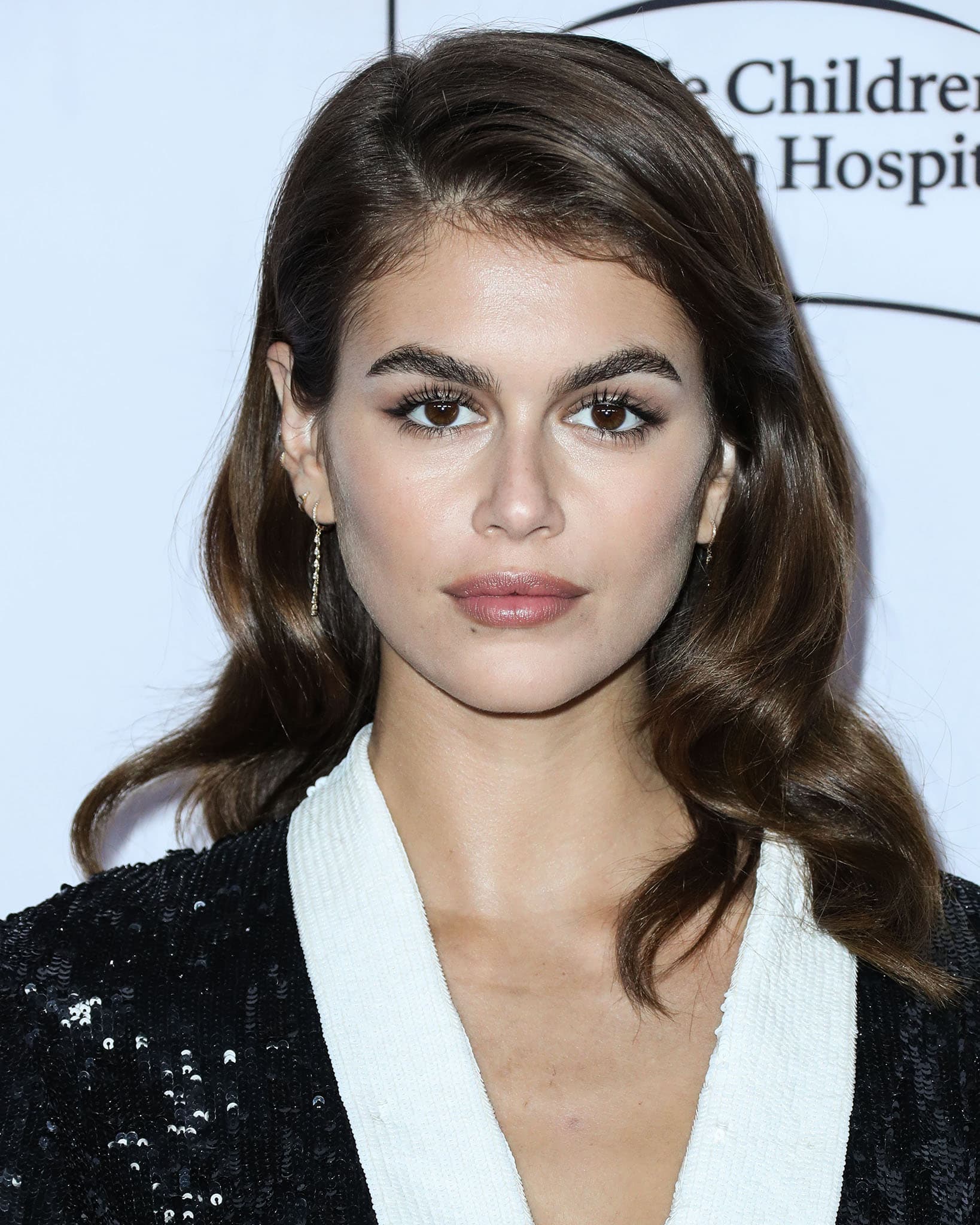 Kaia Gerber glams up with bronze eyeshadow, winger eyeliner, nude lipstick and slightly teased retro loose waves