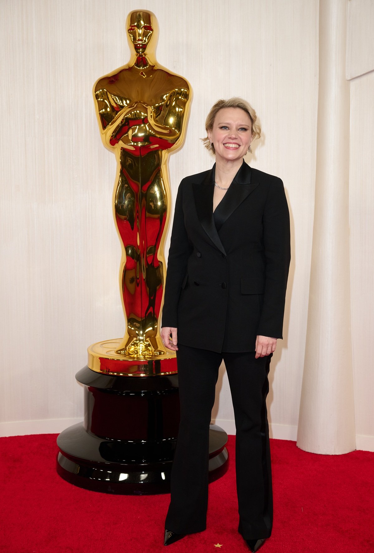 Kate McKinnon attends the 96th Oscars at the Dolby Theatre at Ovation Hollywood on March 10, 2024, wearing a custom Akris suit styled by Rebecca Grice. She completed the look with black patent Stuart Weitzman Stuart 100 Pumps and Bucherer fine jewelry — a sleek, confident ensemble for presenting the Best Documentary Short and Feature awards alongside America Ferrera