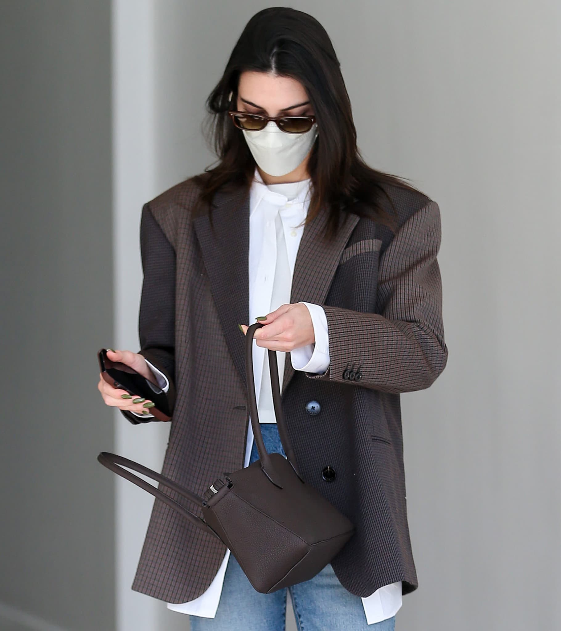 Kendall Jenner wears her brunette hair down and styles her look with Salt sunglasses and The Row East-West bag