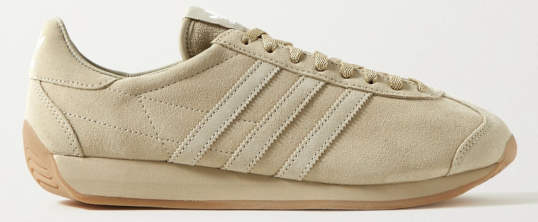 These Khaite + Adidas Originals sneakers have sand suede uppers subtly detailed with the iconic side stripes and set on a streamlined rubber sole