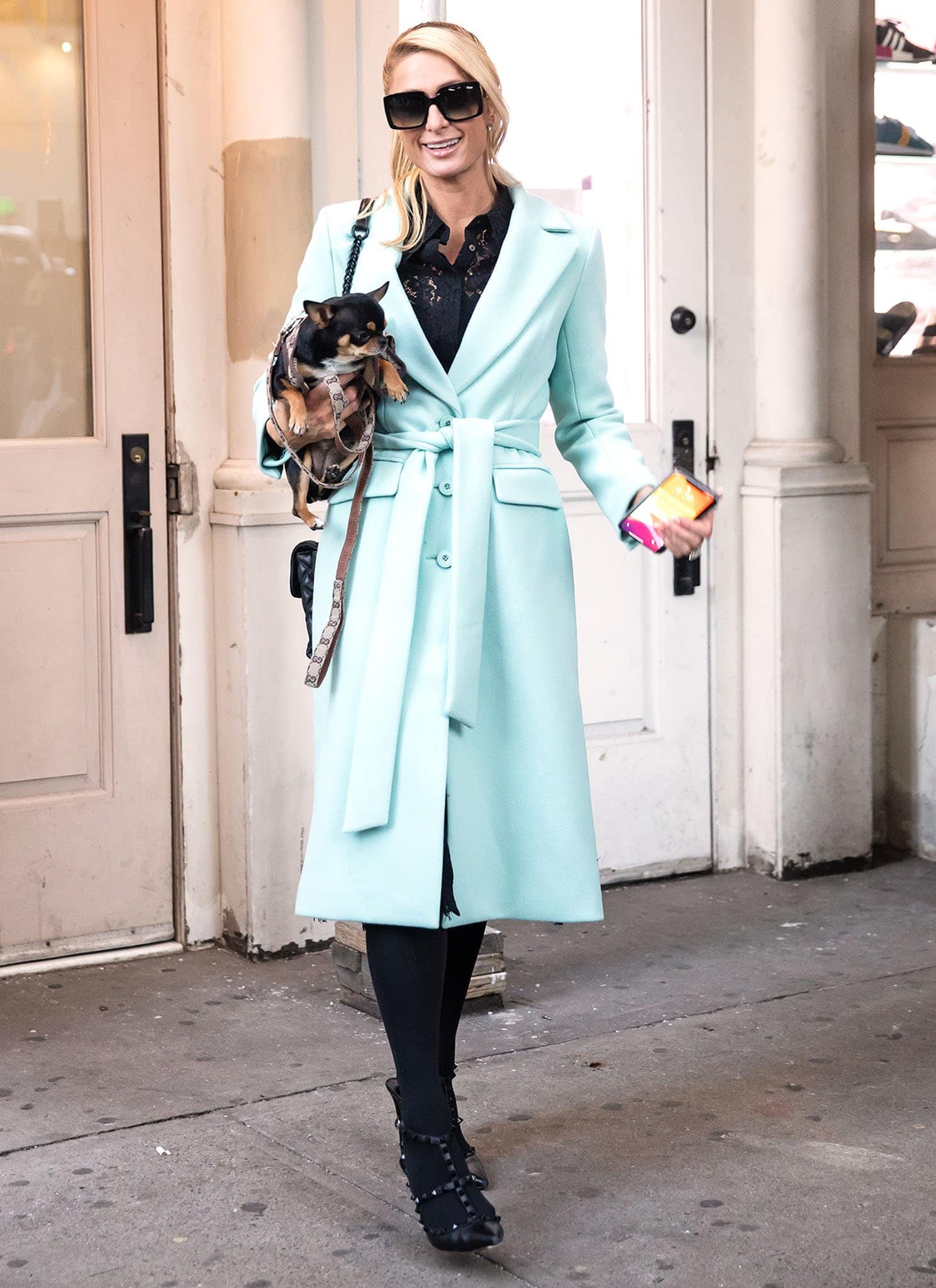 Paris Hilton wearing a chic teal coat with a black lace blouse and tights