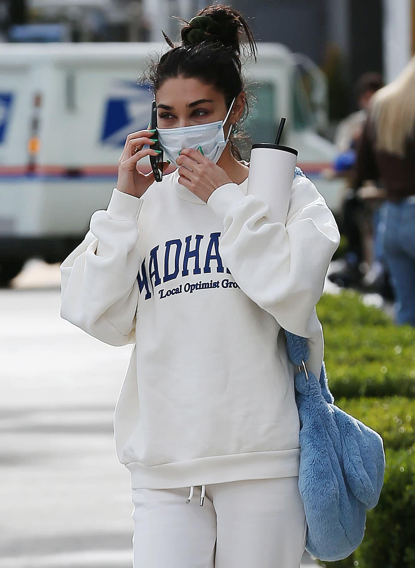 Vanessa Hudgens completes her laidback look with a messy topknot, a fuzzy blue bag, and a face mask