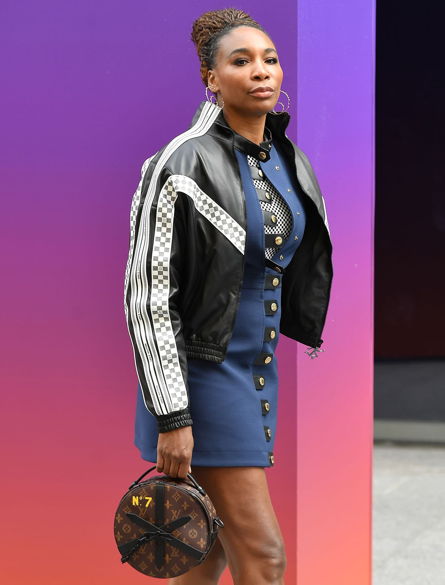 Venus Williams wears her tresses in a sleek updo and styles her look with hoop earrings and a Louis Vuitton round bag