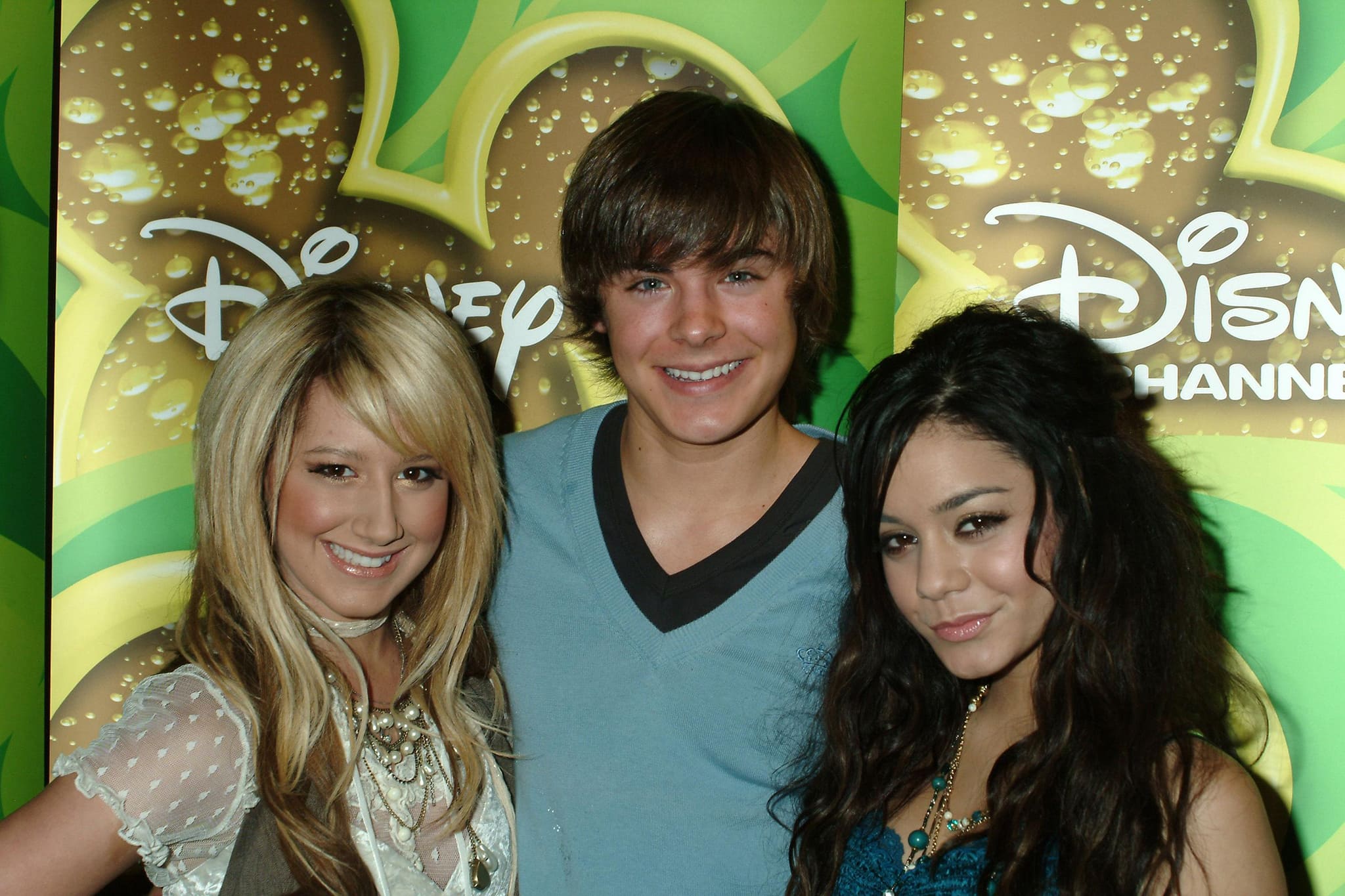 Ashley Tisdale, Zac Efron and Vanessa Hudgens pose for photos in front of a Disney Channel-branded backdrop
