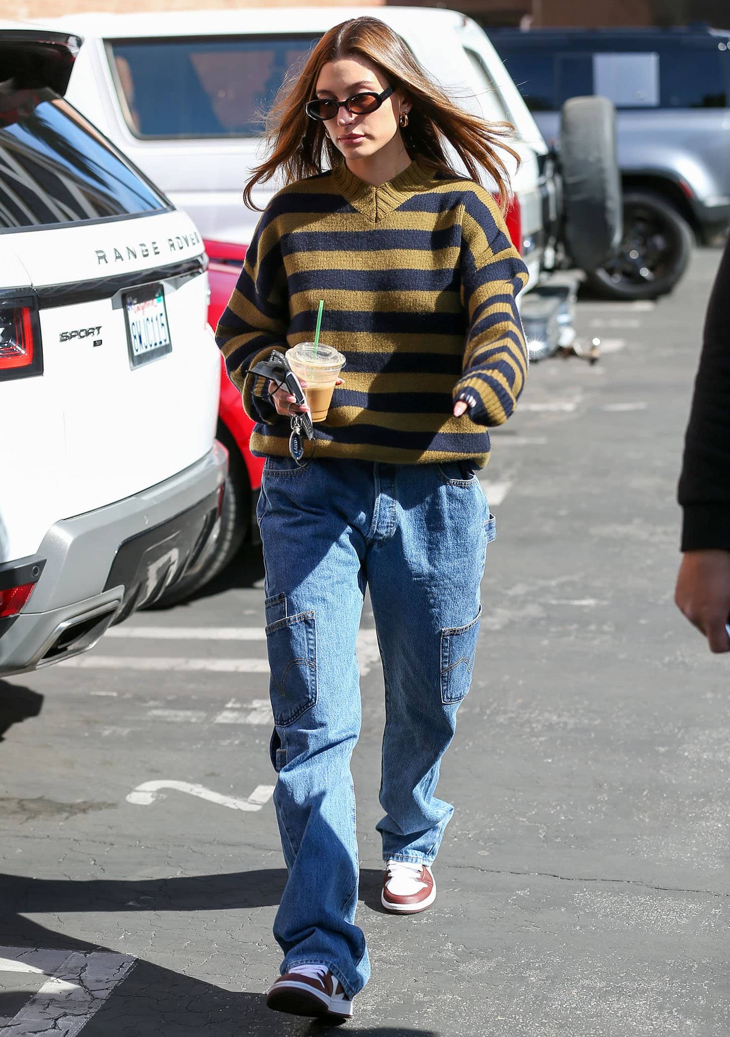 Hailey Bieber runs errands in Extreme Cashmere striped sweater and Maryam Nassir Zadeh straight-leg cargo jeans on February 8, 2022