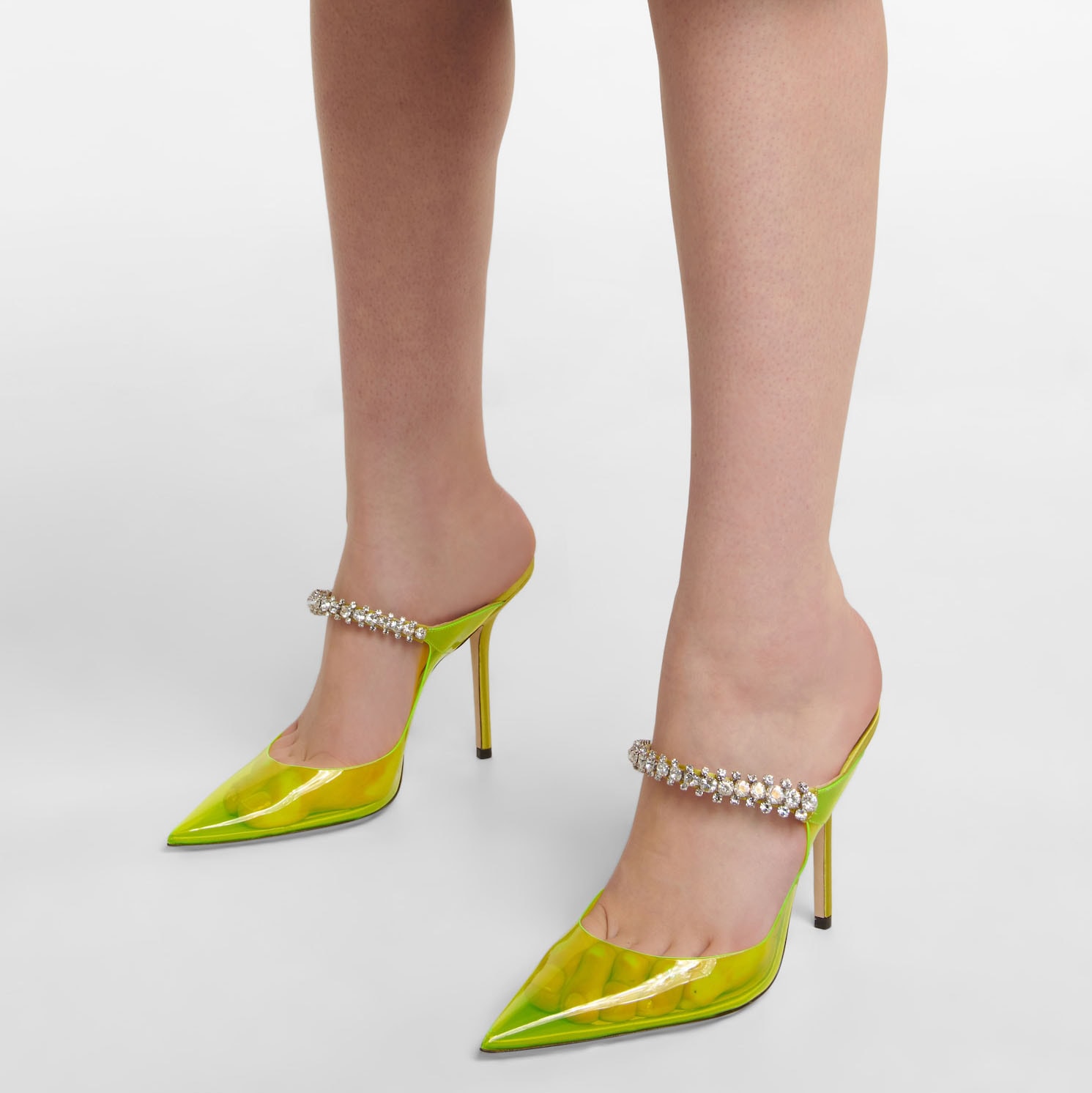 Providing timeless elegance with a contemporary twist, the Bing mules are designed from neon yellow PVC elevated with a crystal-embellished strap