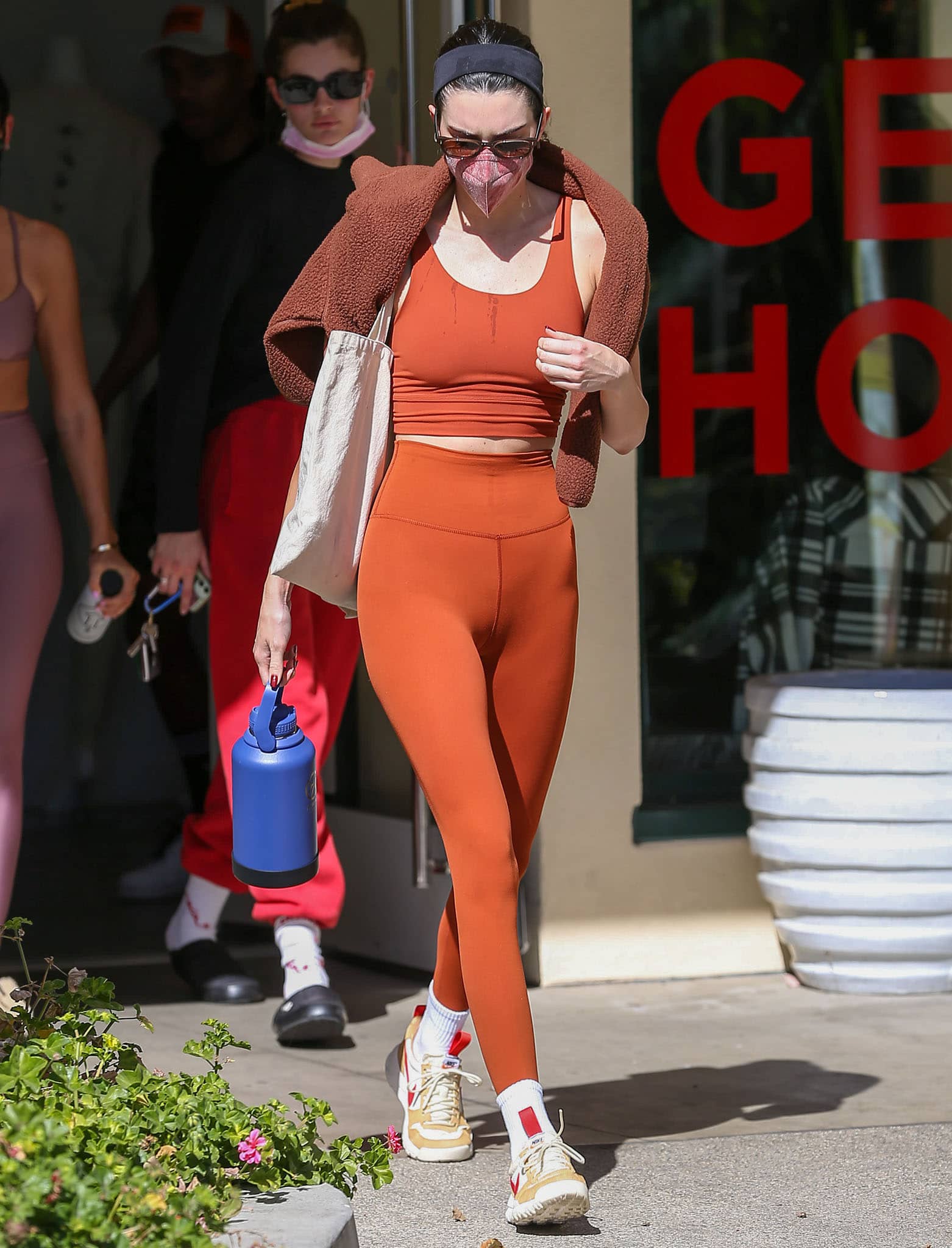 Kendall Jenner in autumnal orange activewear and fuzzy brown sweater