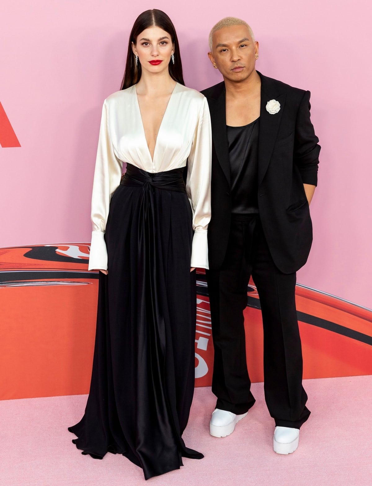 Camila Morrone in a Prabal Gurung Pre-Fall 2019 twist front satin gown posing with fashion designer Prabal Gurung at 2019 CFDA Fashion Awards