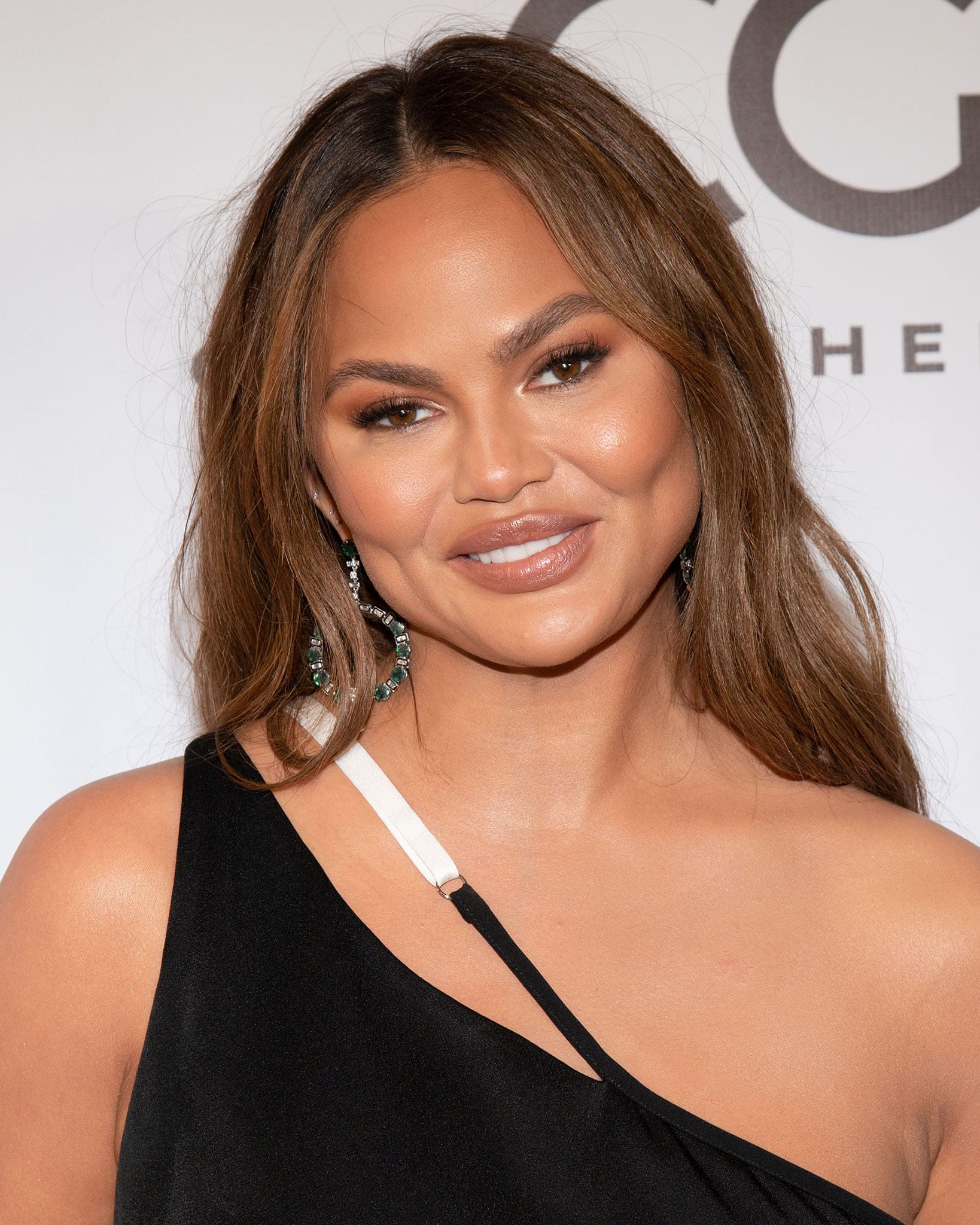 Chrissy Teigen styles her tresses in beach waves and glams up with neutral makeup