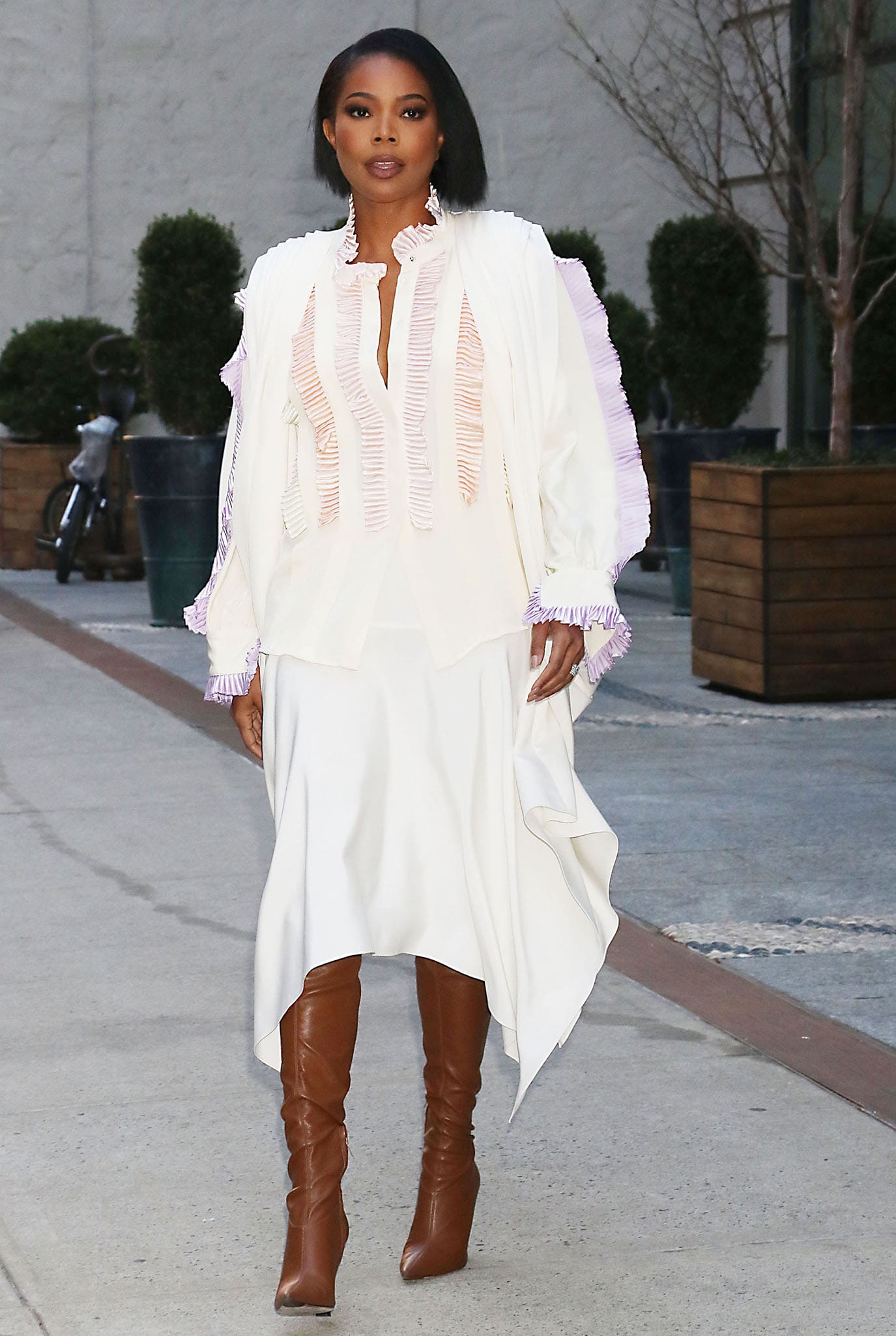 Gabrielle Union leaving The View in white dress with plisse trims and brown leather boots