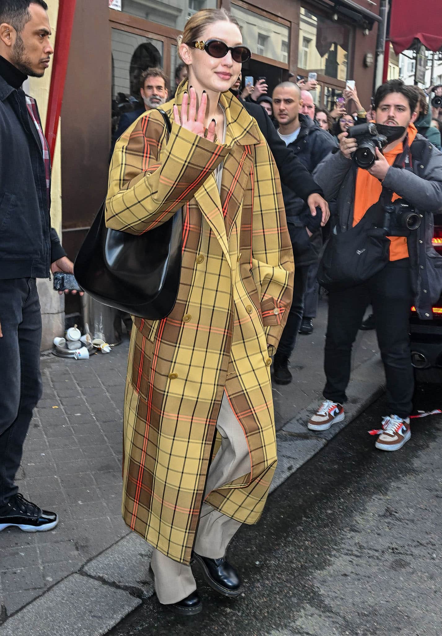 Gigi Hadid wears a yellow tartan trench coat from Vivienne Westwood's Spring 2022 collection outside Nouvelle Eve ahead of the fashion show