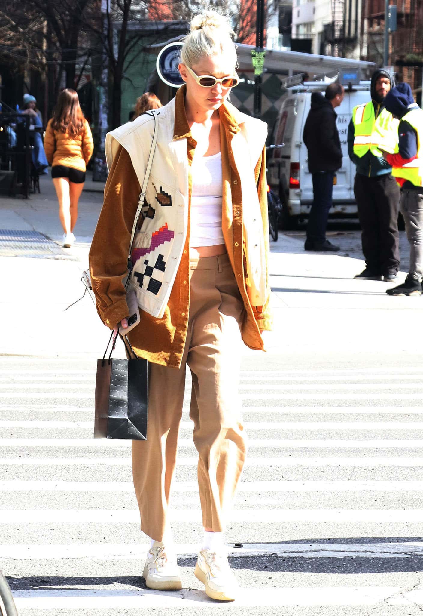 Gigi Hadid looks chic in a white tank top, khaki pants, tan shirt, and Isabel Marant embroidered vest