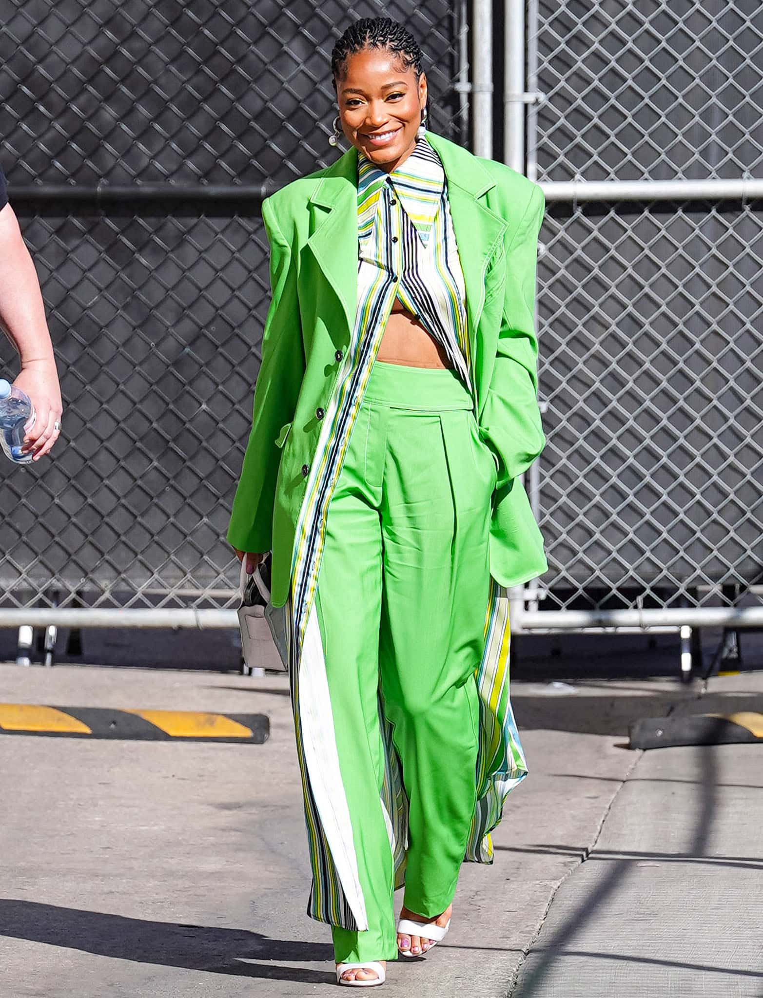 Keke Palmer pairs her green suit with multicolored striped shirt dress and Dolce & Gabbana white heels
