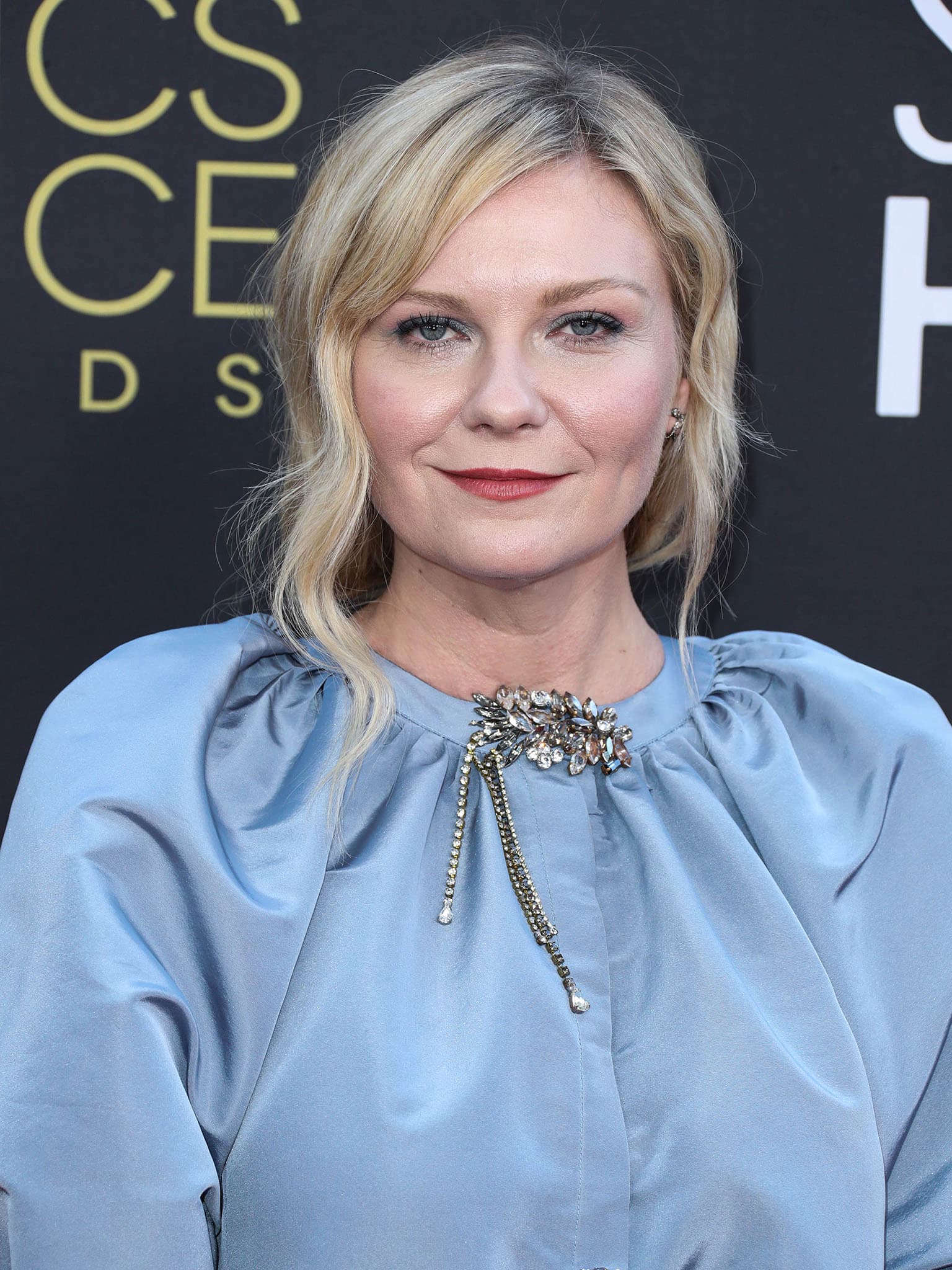 Kirsten Dunst coordinates her dress with her makeup with blue eyeshadow and red lipstick