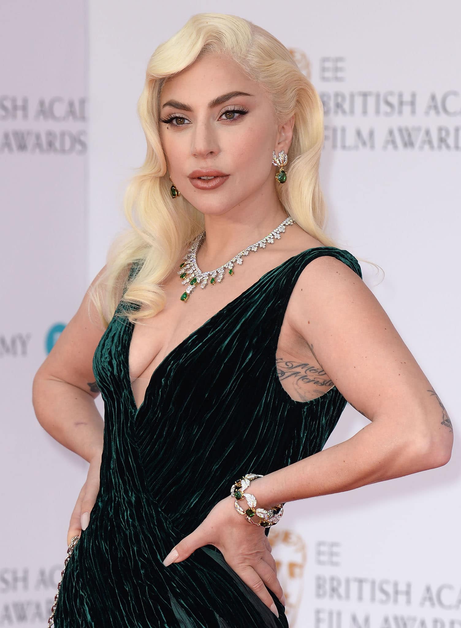 Lady Gaga styles her forest green gown with emerald jewelry by Tiffany & Co. and wears old Hollywood curls and makeup