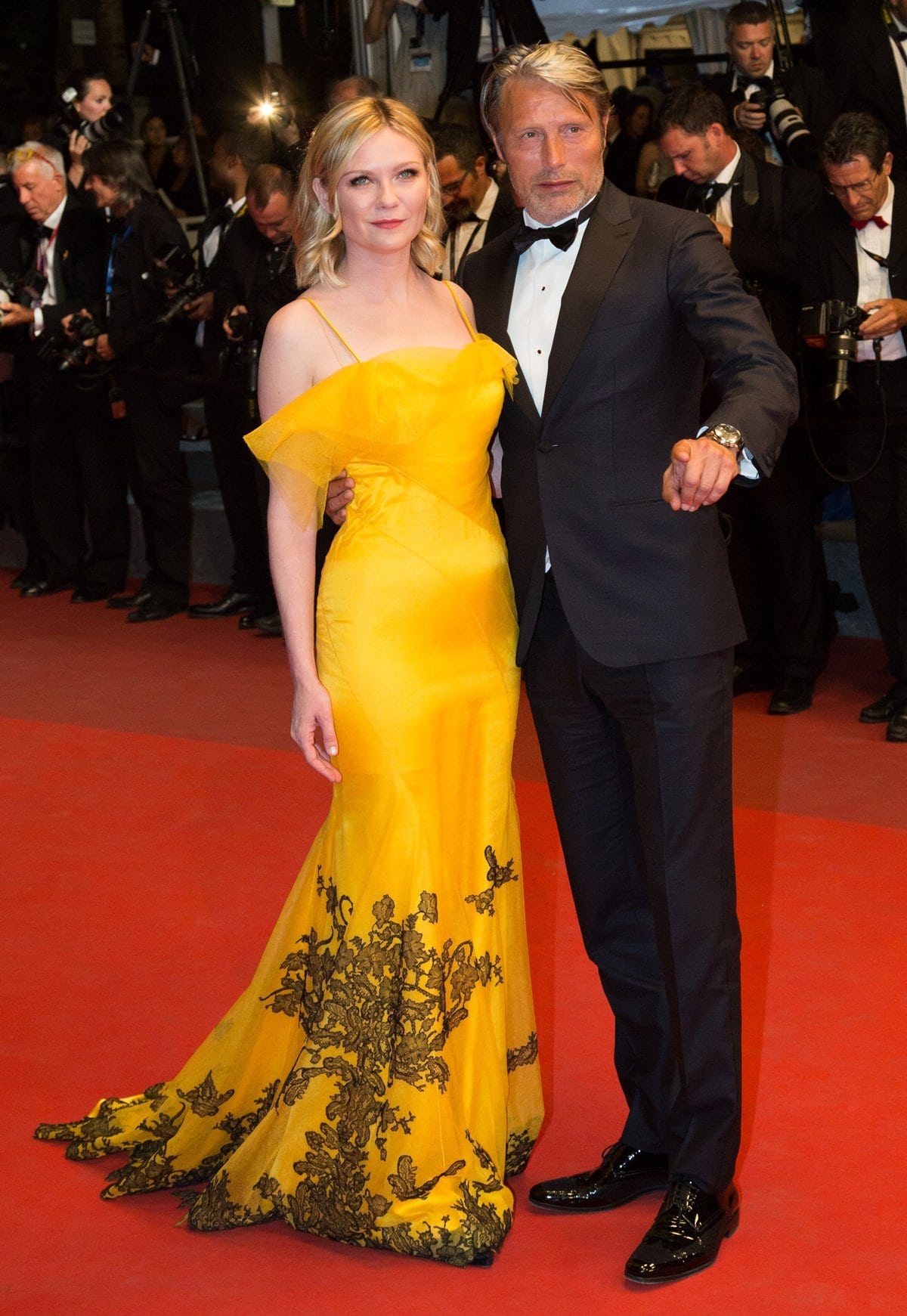 Mads Mikkelsen with Kirsten Dunst in a custom Maison Margiela by John Galliano marigold satin and tulle overlay gown featuring leaf detailing at 'The Neon Demon' premiere