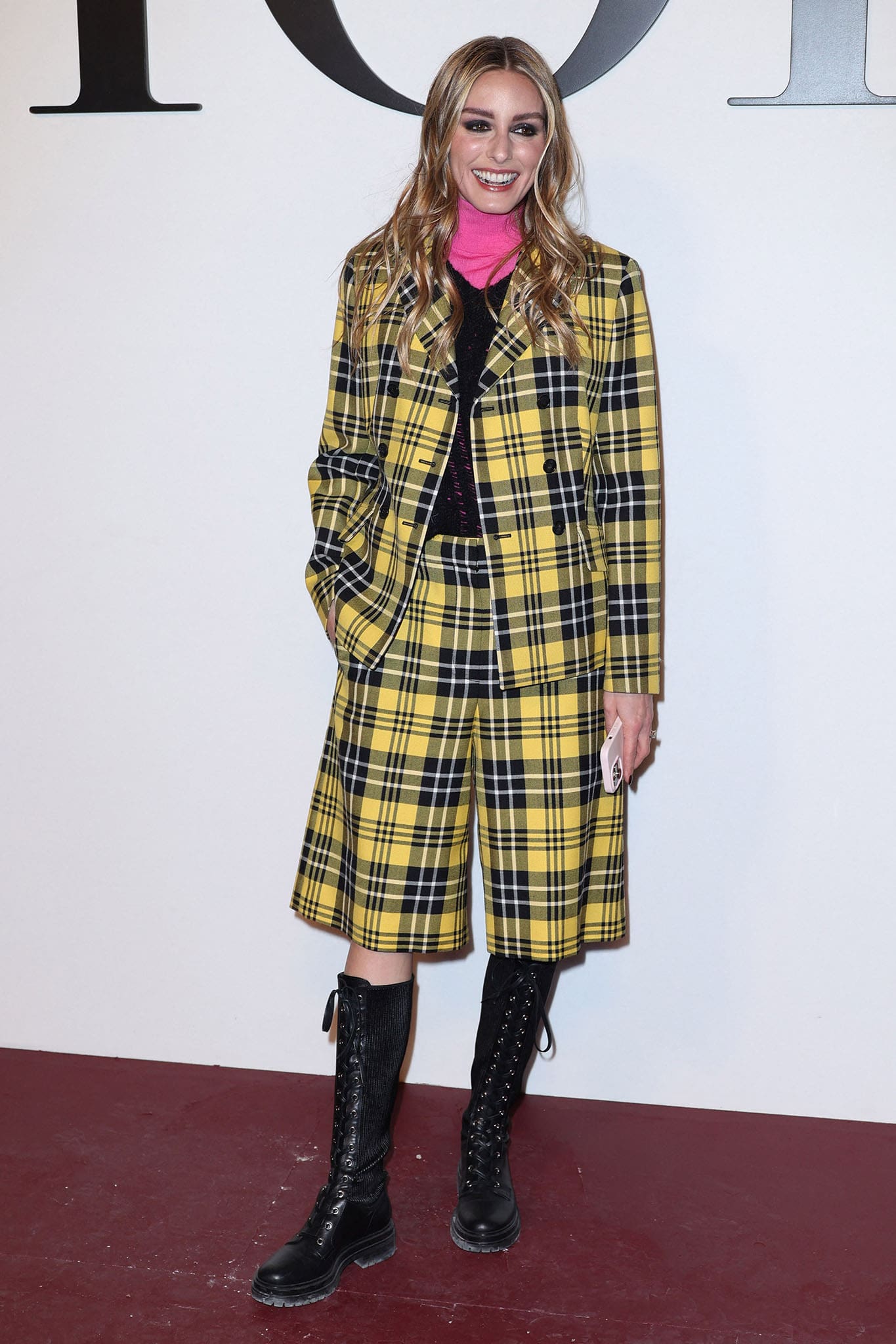 Olivia Palermo wears a Clueless-inspired yellow tartan jacket and matching culottes with knee-high combat boots at the Dior Paris Fashion Week show on March 1, 2022