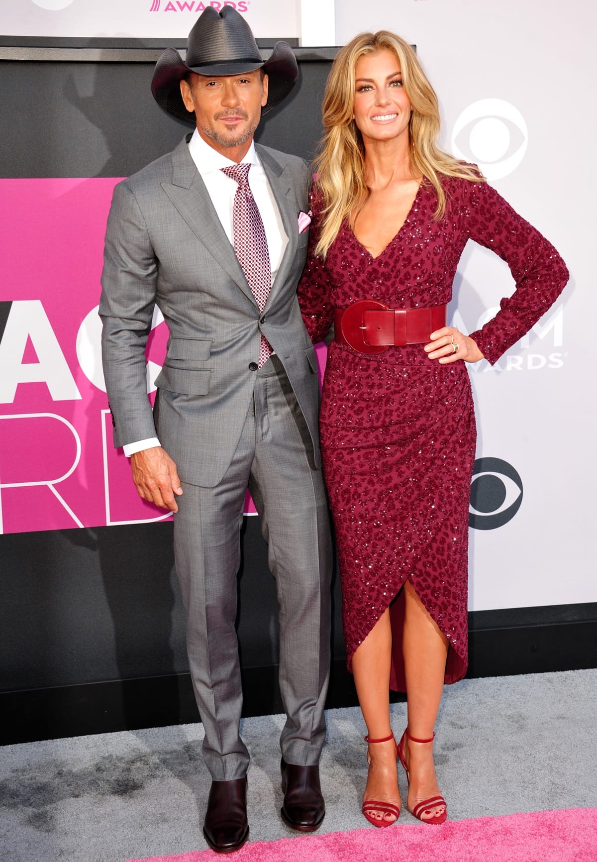 Tim McGraw looks sharp in a tailored gray suit and signature cowboy hat, while Faith Hill stuns in a burgundy sequined dress paired with matching red ankle-strap heels at the ACM Awards