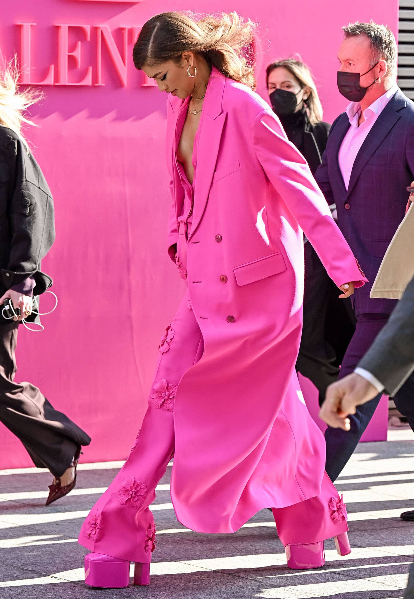 Zendaya goes braless underneath her Valentino pink coat, pink blouse, and pink suit with floral appliques