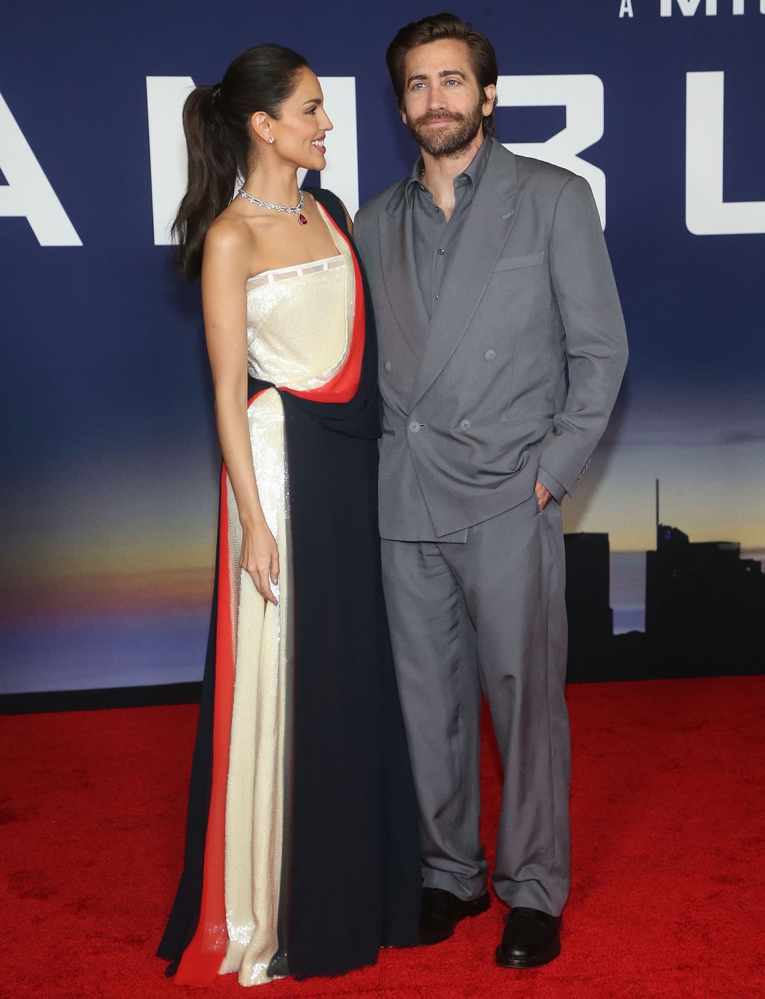 Eiza Gonzalez poses alongside lead star Jake Gyllenhaal, who looks dapper in a gray suit