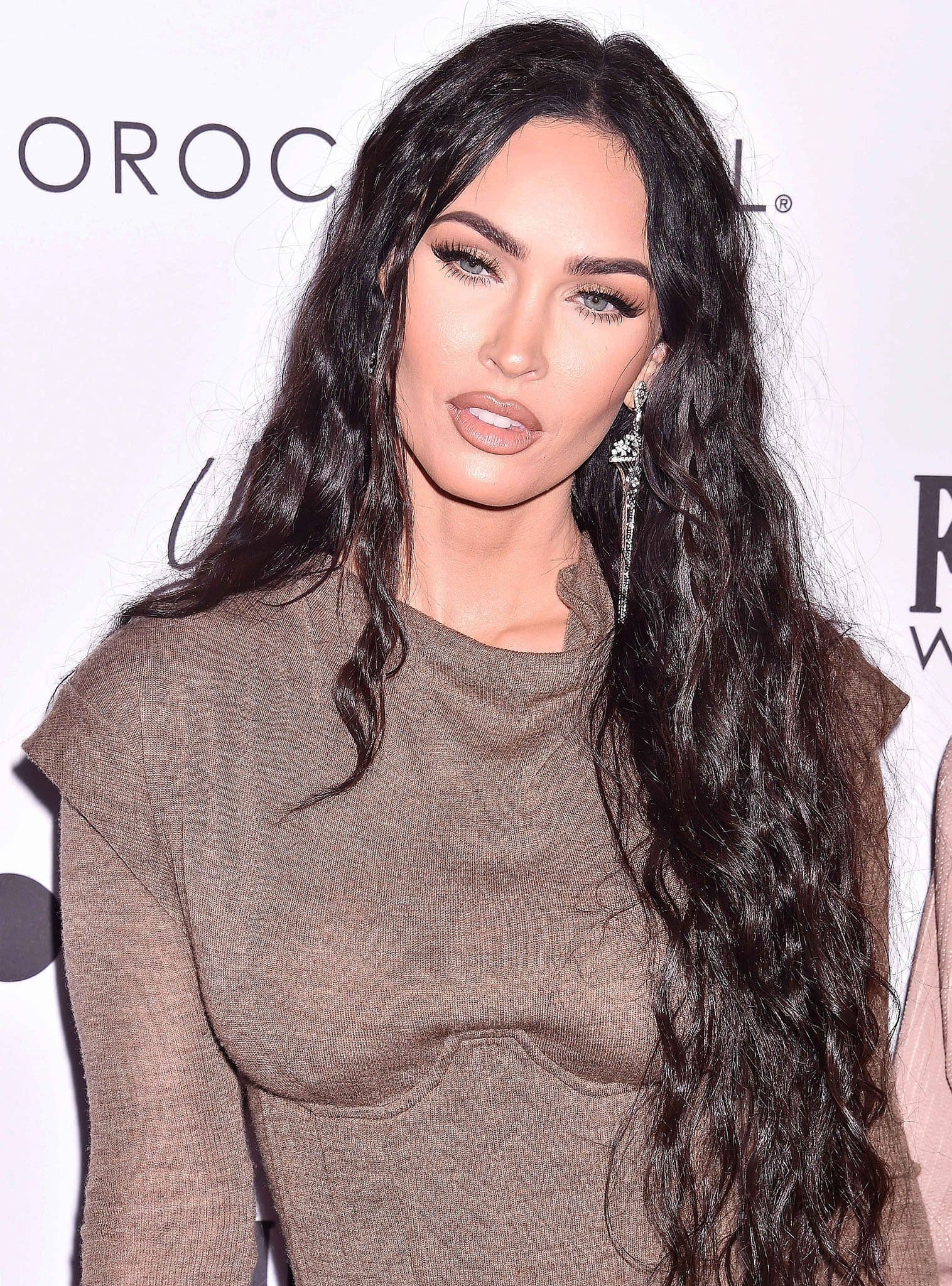 Megan Fox wears her long tresses in thick curls and highlights her features with nude makeup
