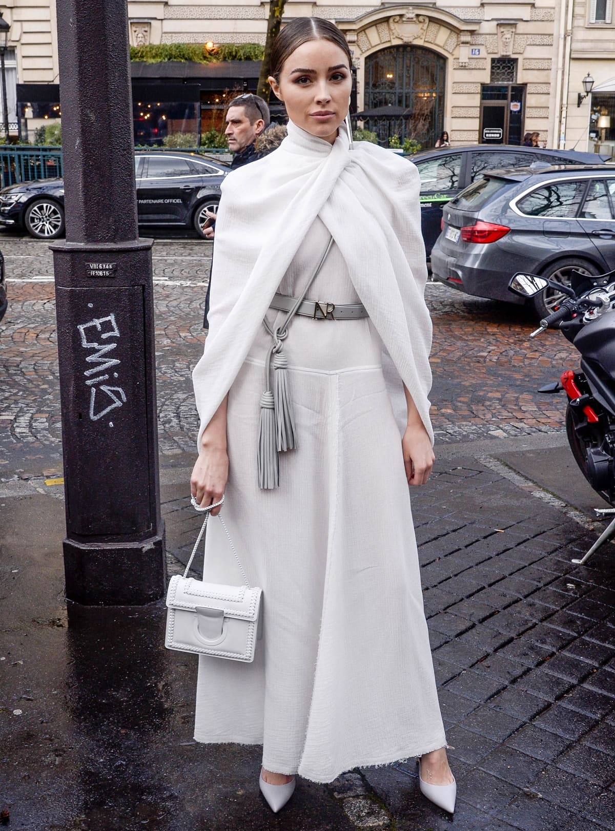 Olivia Culpo wearing a white Nina Ricci cape dress with a Salvatore Ferragamo Gancio bag, Casadei heels, Maria Black jewelry for the Nina Ricci show