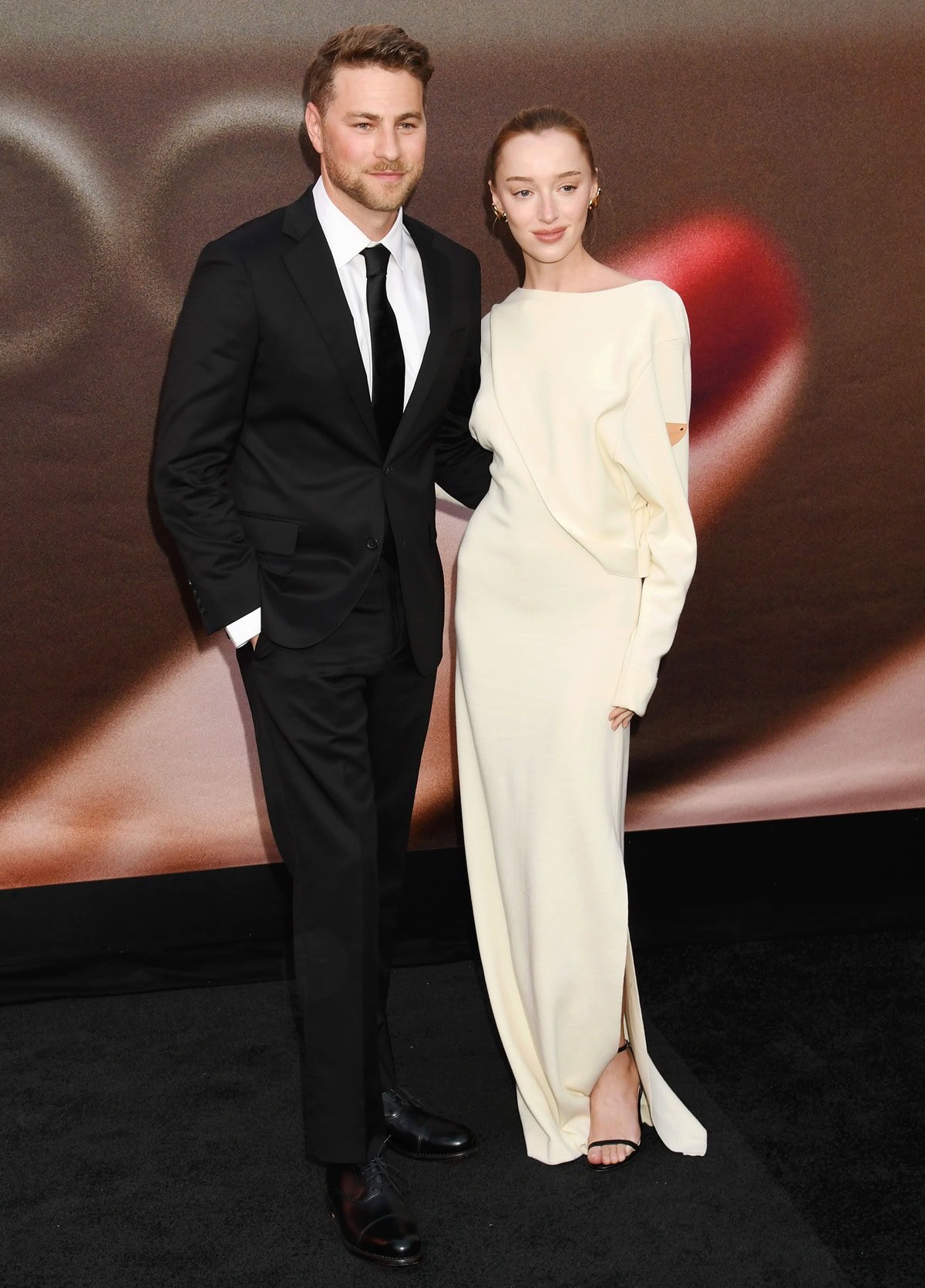 Phoebe Dynevor walked the red carpet with fiancé Cameron Fuller, wearing a minimalist white Louis Vuitton gown styled with Jimmy Choo Minny sandals and Tiffany & Co. Elsa Peretti 18K gold Bean earrings at the Los Angeles premiere of The Drop on April 8, 2025