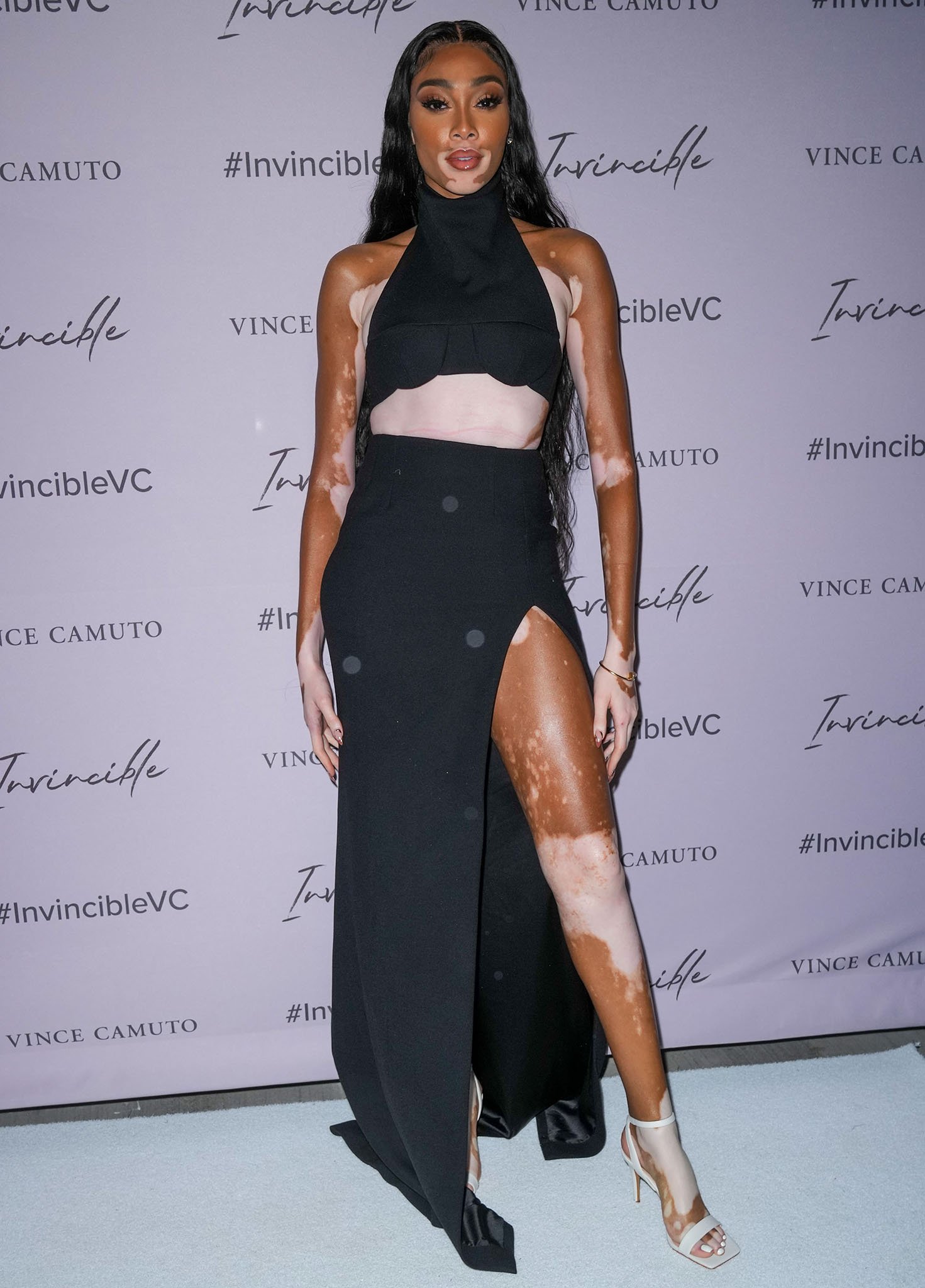 Winnie Harlow showcases her toned abs and legs in a halter-neck crop top and a maxi skirt with thigh-high slit from LaQuan Smith