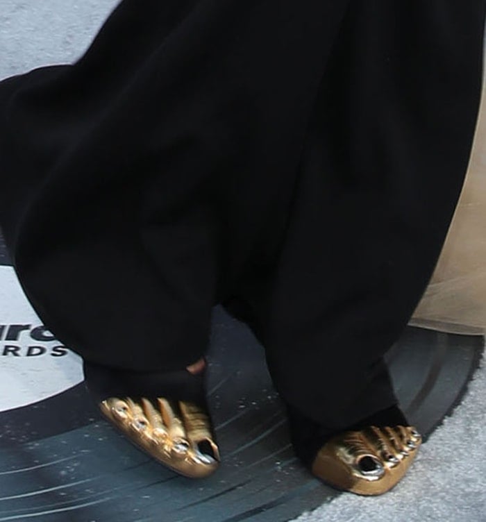 Doja Cat slips her feet into Schiaparelli's black satin mules with golden toes and silver nails