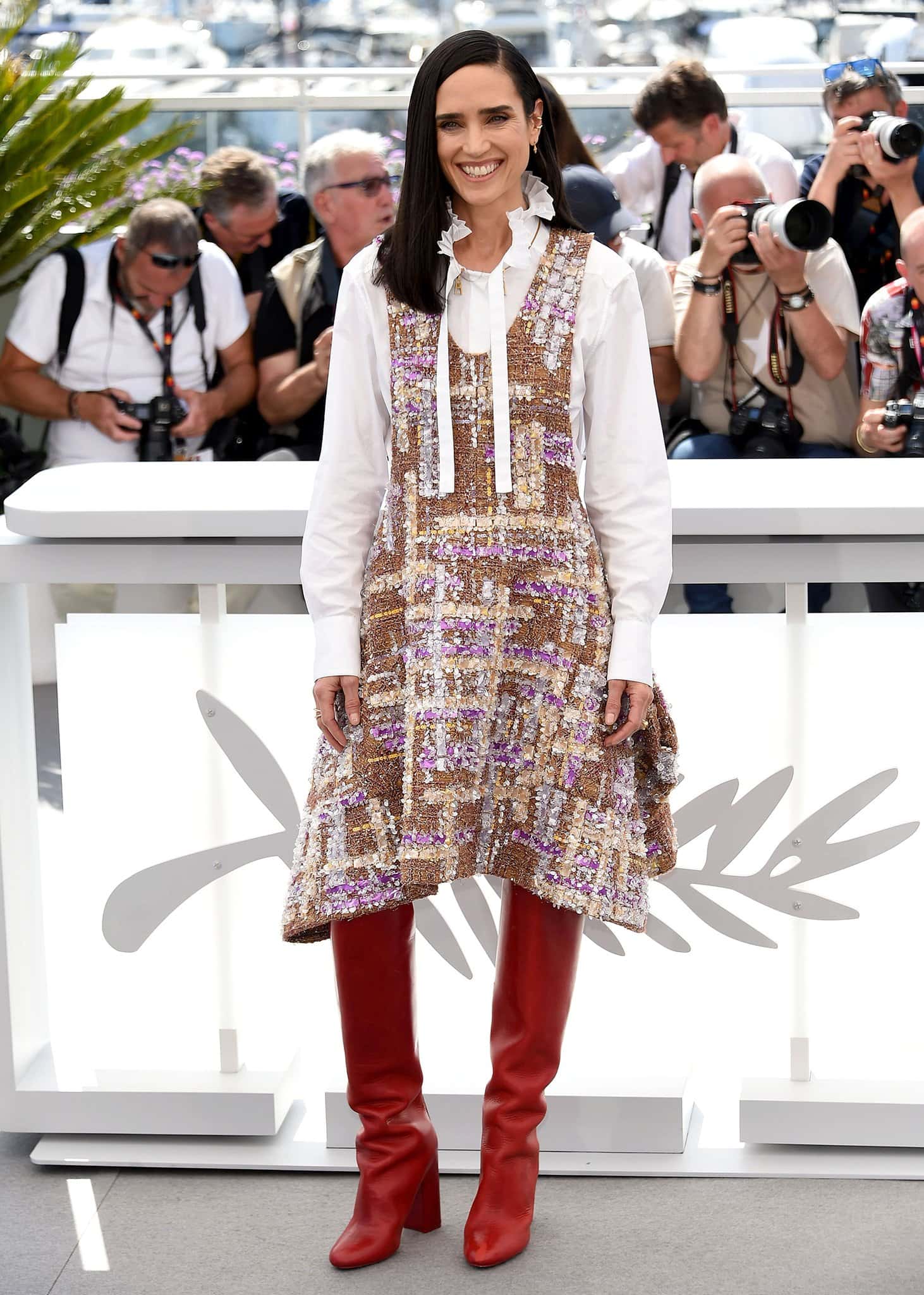 Jennifer Connelly dons a Louis Vuitton white ruffled shirt underneath a tweed dress with red knee-high boots