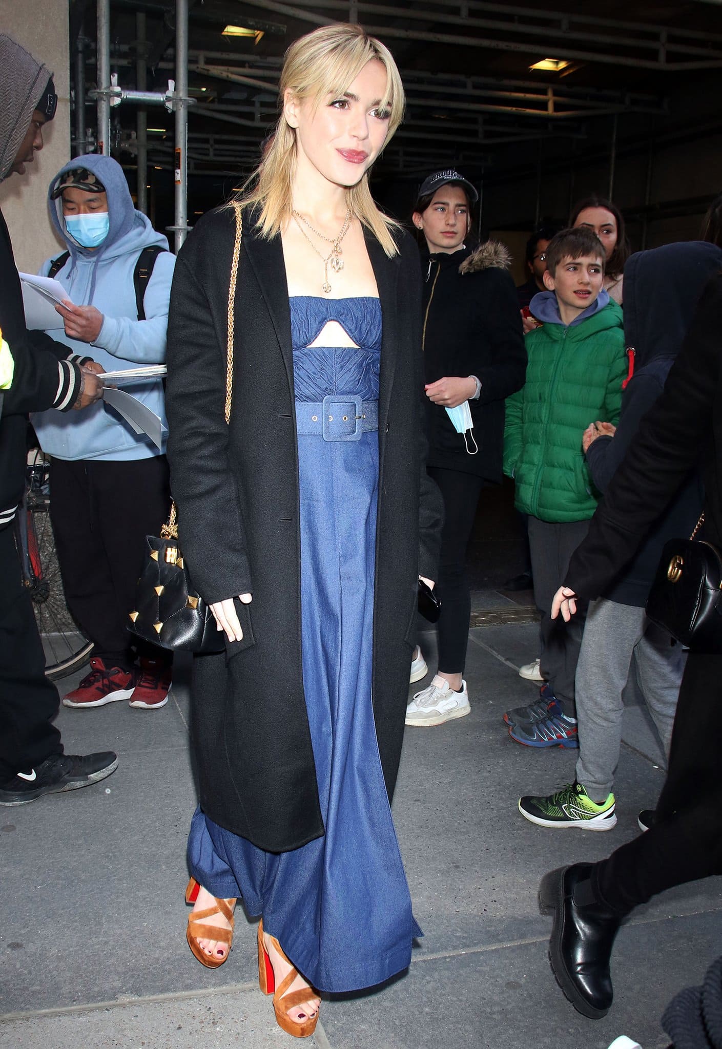 Kiernan Shipka arriving at The Today Show in a blue maxi dress with a black trench coat on April 28, 2022