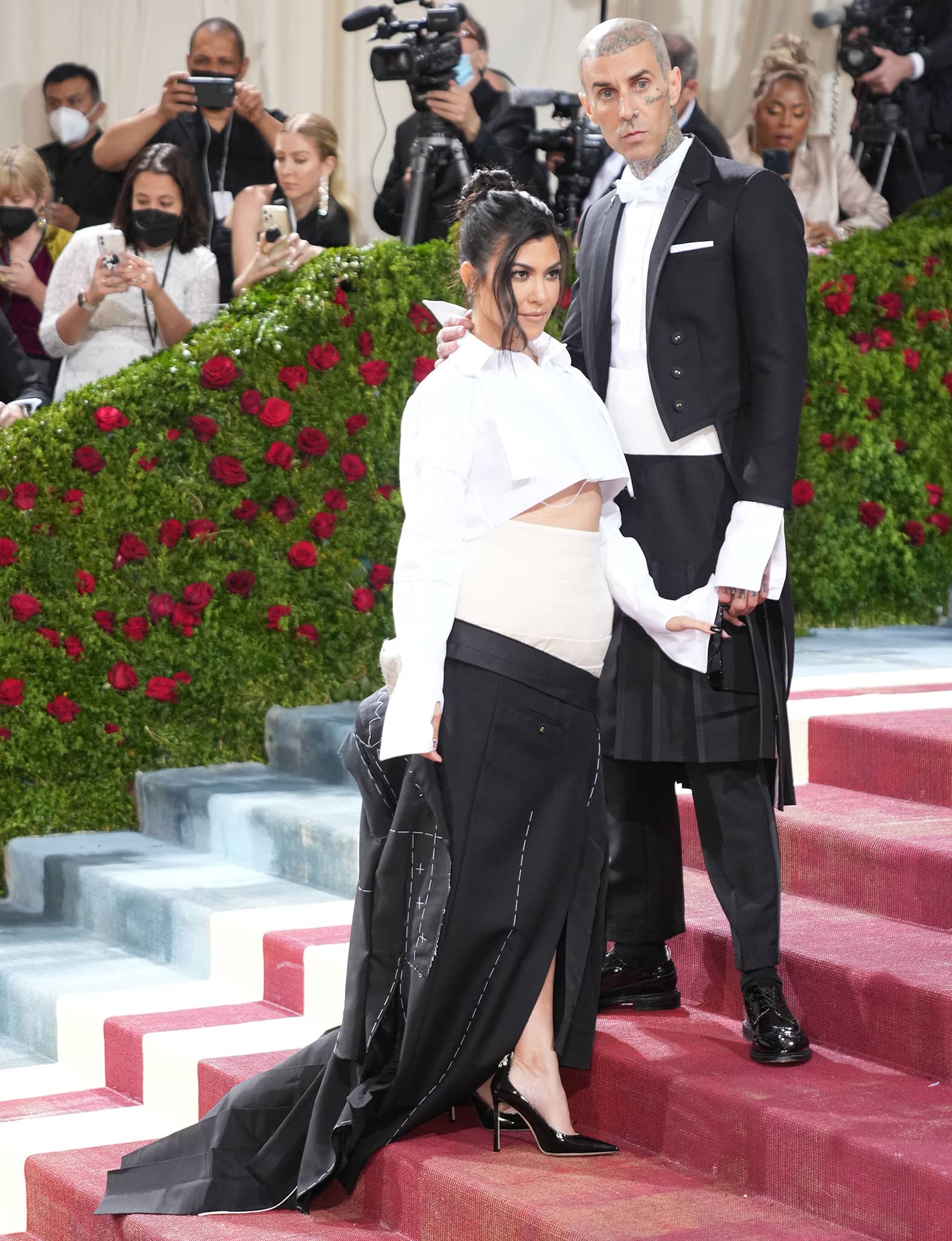 Travis Barker wears a tailcoat with a cummerbund and a kilt, while Kourtney dons a deconstructed version of her fiancé’s outfit