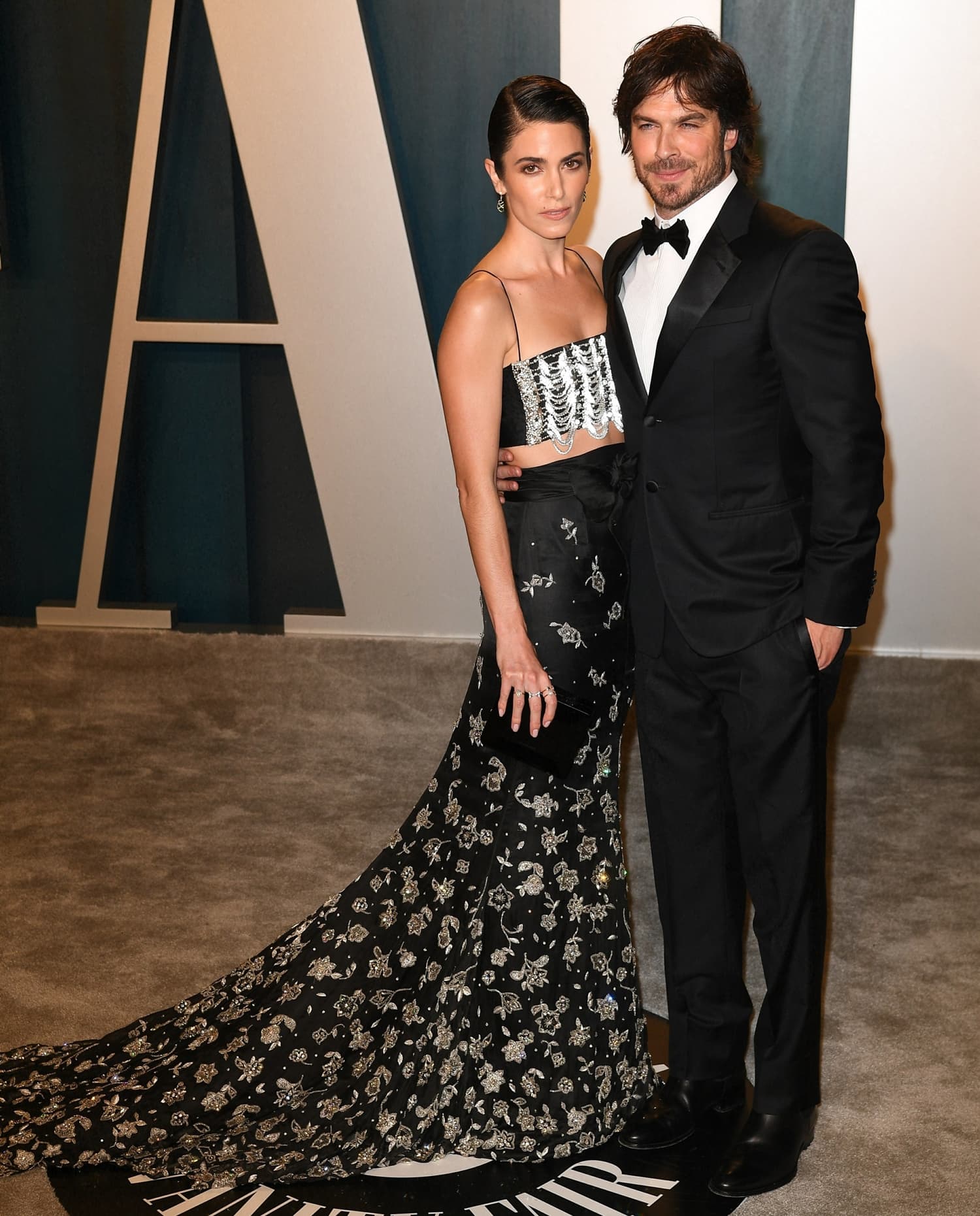 Nikki Reed stuns in a silver embroidered Armani Privè bandeau top and a black silk skirt adorned with intricate floral details, attending the 2020 Vanity Fair Oscar Party alongside her husband Ian Somerhalder