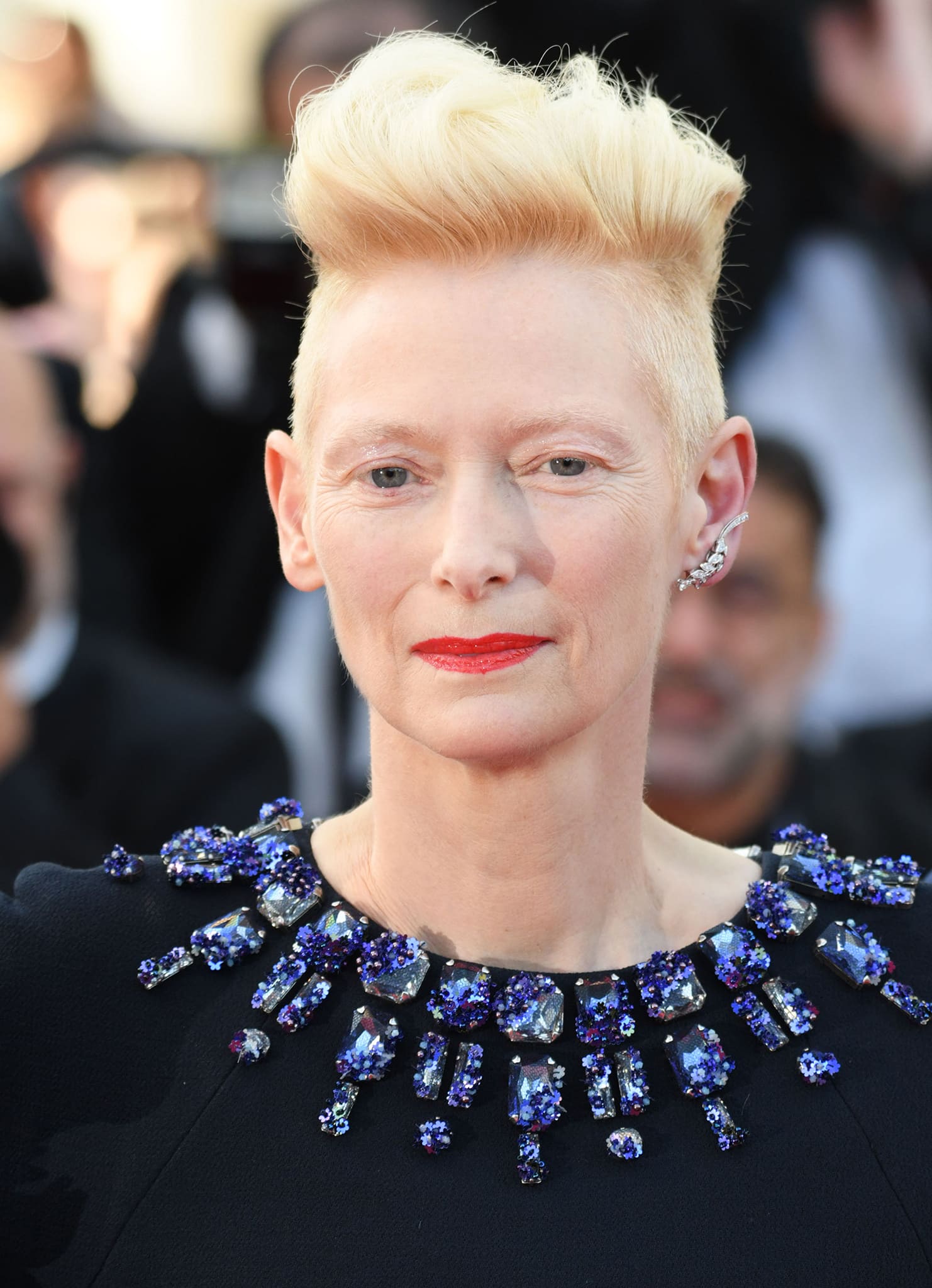 Tilda Swinton wears her signature blonde mohawk hairstyle and sports minimal makeup with red lipstick