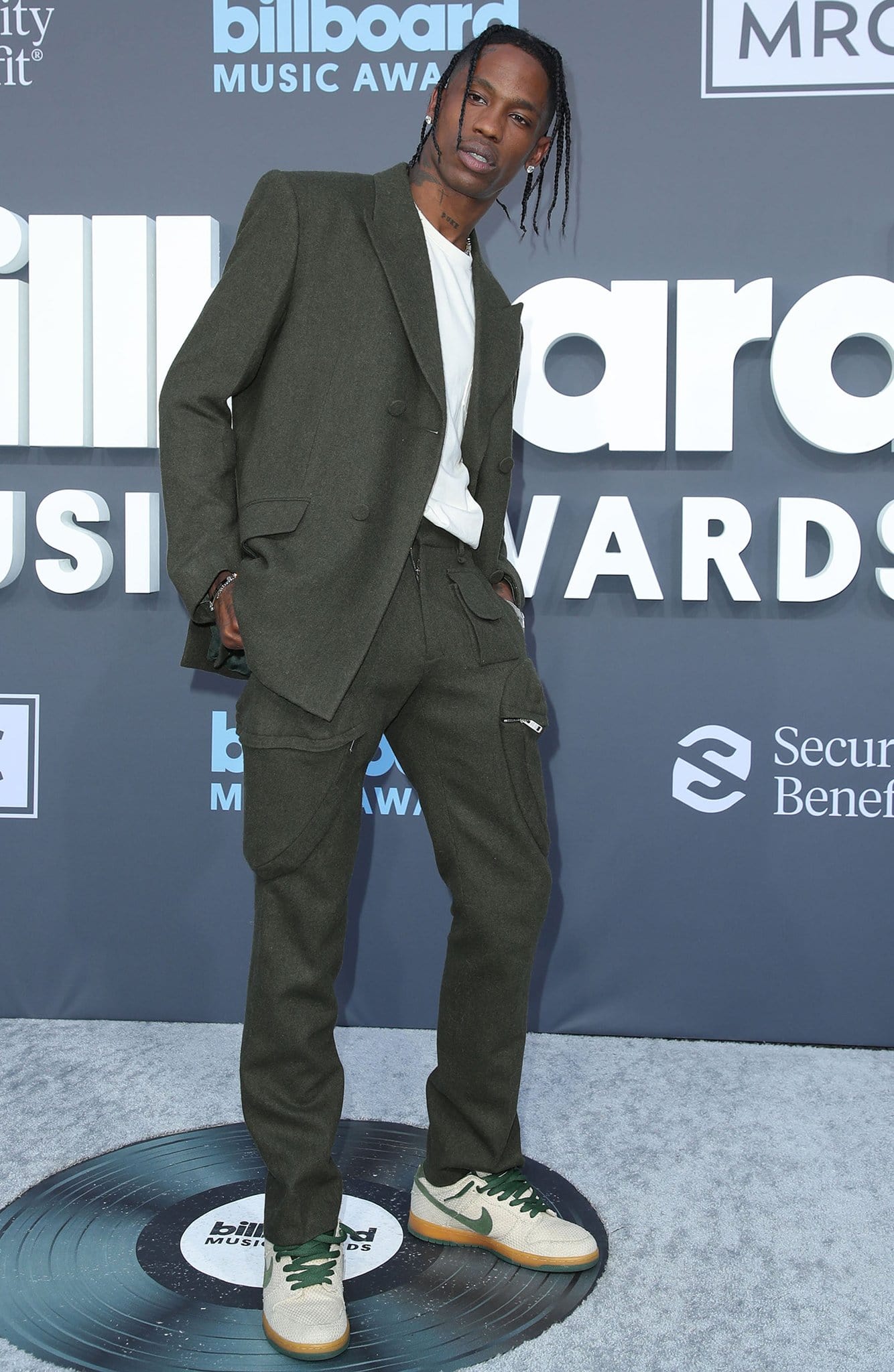 Travis Scott wears an olive-green Givenchy Fall 2022 suit with Nike sneakers