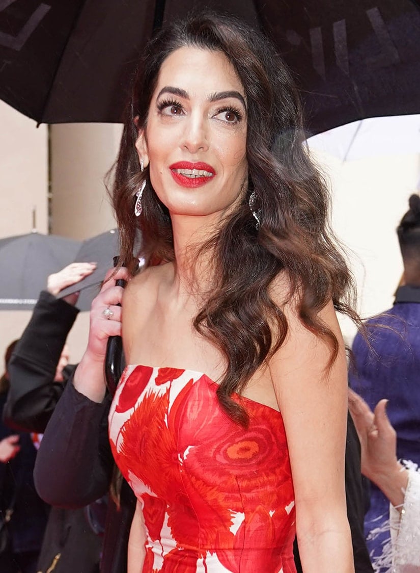 Amal Clooney completes her look with matching red lipstick and her signature side-swept curls