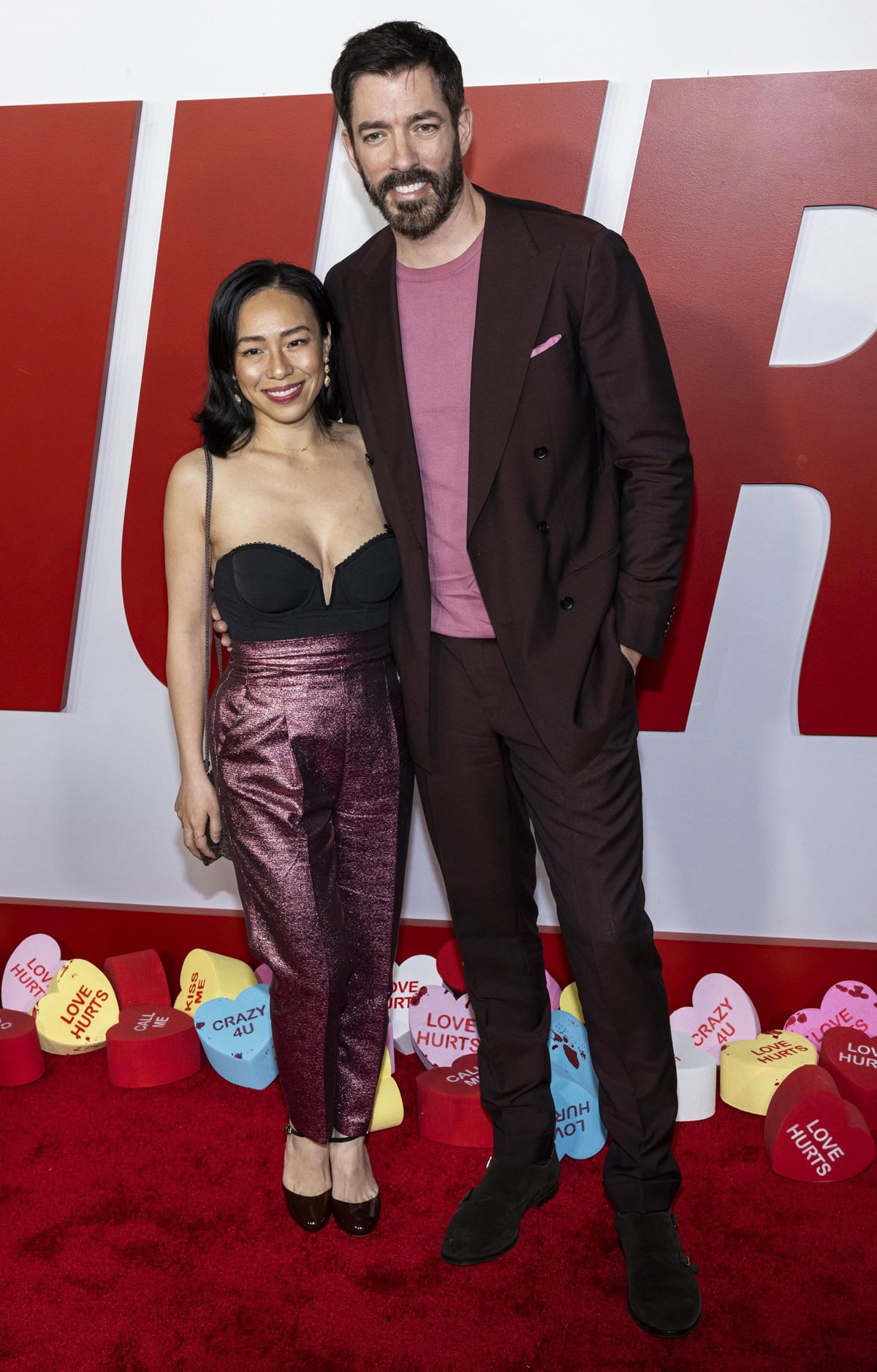Drew Scott towers over his 5-foot-tall wife, Linda Phan, who adds a few extra inches in dark platform heels while rocking sparkly high-waisted pants and a bustier top at the Premiere of Universal Pictures' "Love Hurts" at TCL Chinese Theatre on February 3, 2025 in Hollywood, California